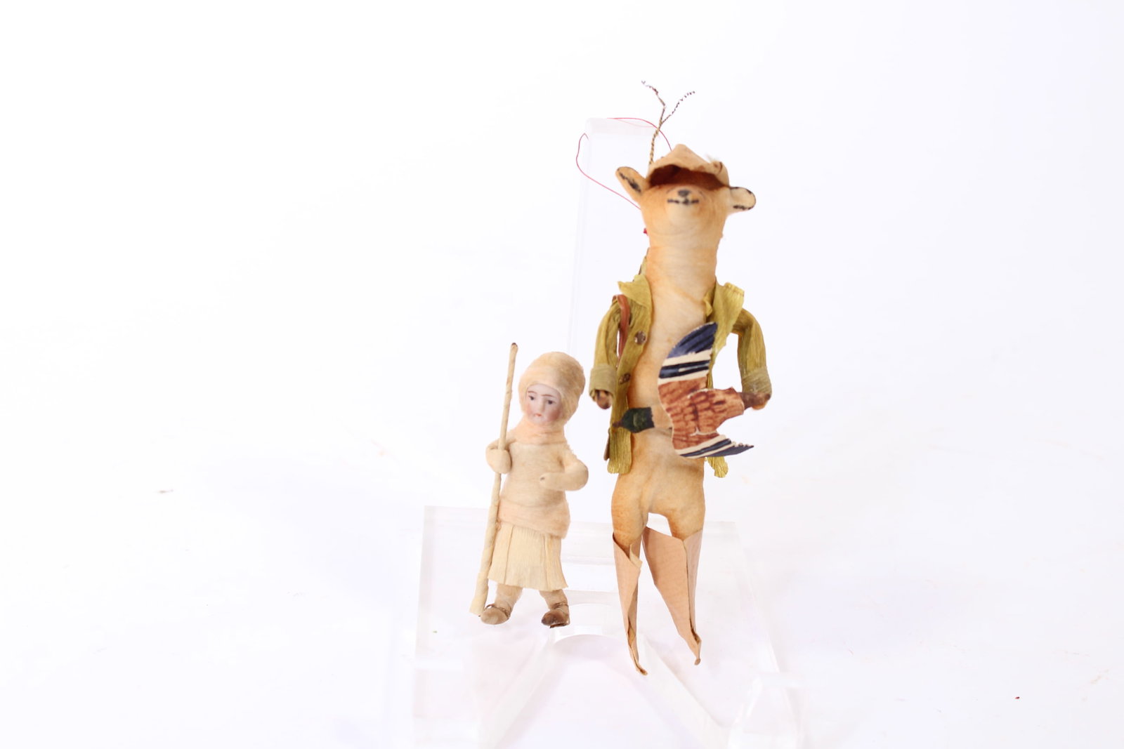 TWO GERMAN FIGURAL CHRISTMAS ORNAMENTS.: TWO GERMAN FIGURAL CHRISTMAS ORNAMENTS. Germany, early 20th Century. A Heubach girl ornament, cotton batting feet, legs, and body, a crepe paper skirt and a porcelain face carrying a long stick, 2.75"
