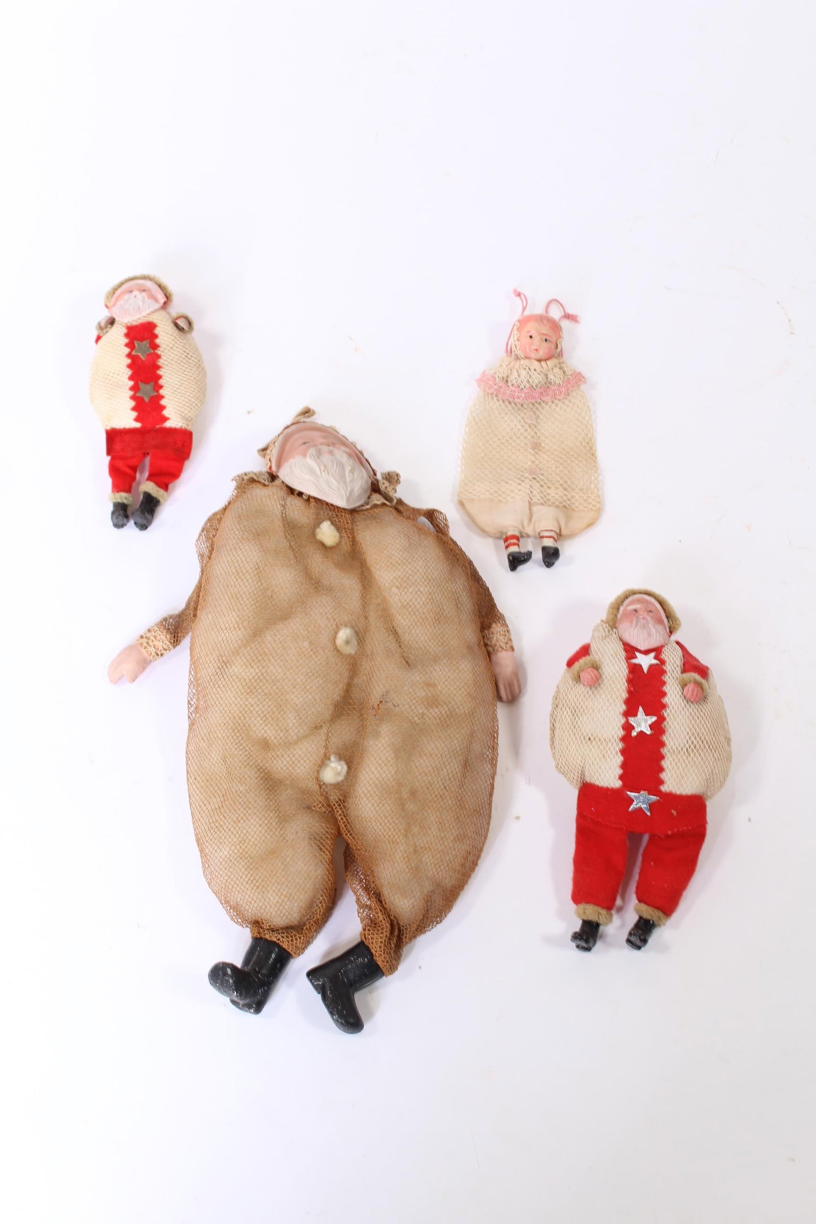 FOUR MESH NETTING FIGURAL CHRISTMAS ORNAMENTS.: FOUR MESH NETTING FIGURAL CHRISTMAS ORNAMENTS. Germany, early 20th Century. Includes a young girl with a plastic head, two Santas with red stripes and silver stars with plastic faces, and a large mesh