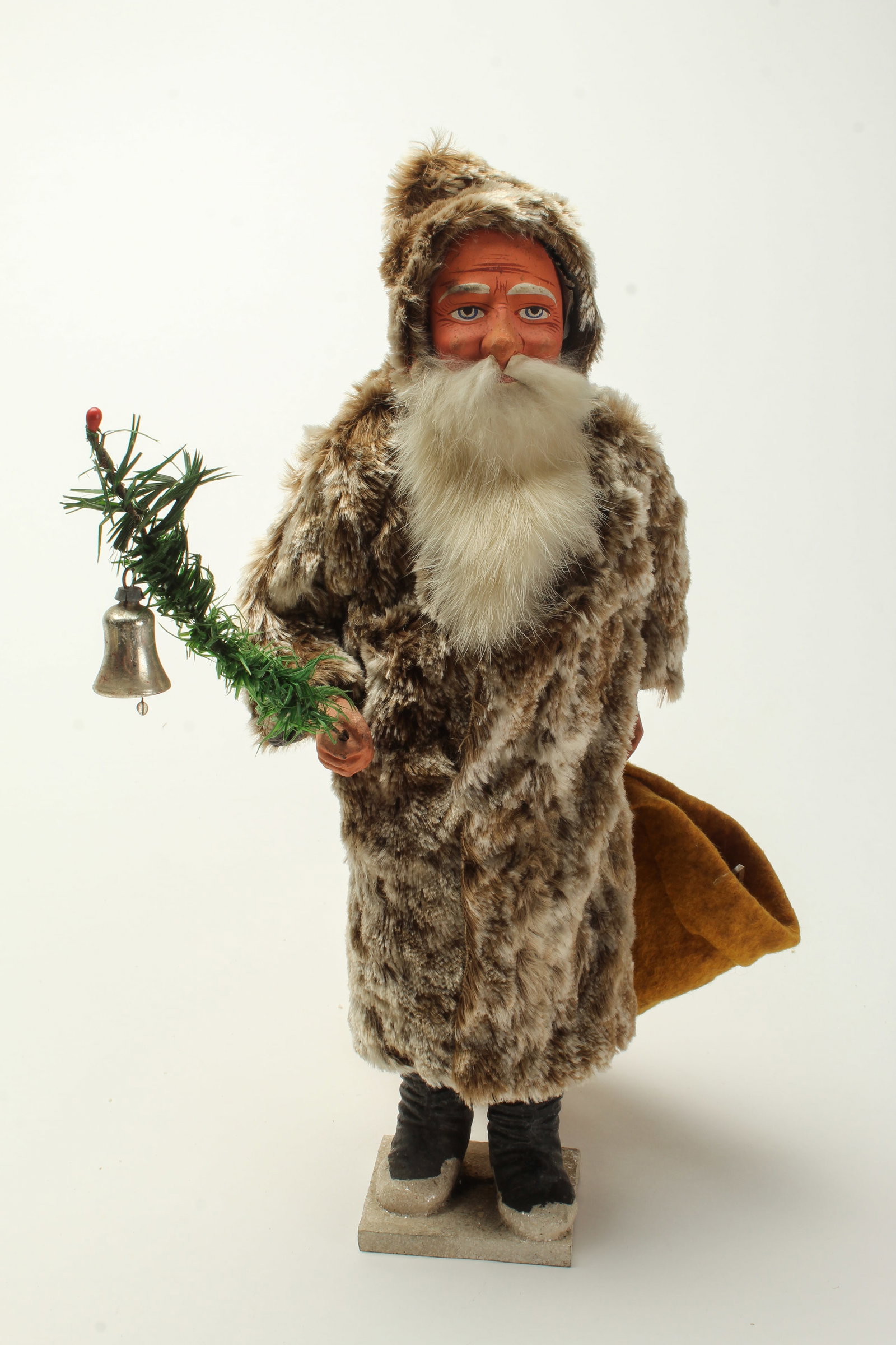 LARGE STANDING SANTA CANDY CONTAINER WITH BROWN COAT AND HOOD.: LARGE STANDING SANTA CANDY CONTAINER WITH BROWN COAT AND HOOD. Germany, early 20th Century. Depicting a standing Santa on a snow-covered base, wearing a long brown and white hooded fur coat, holding a