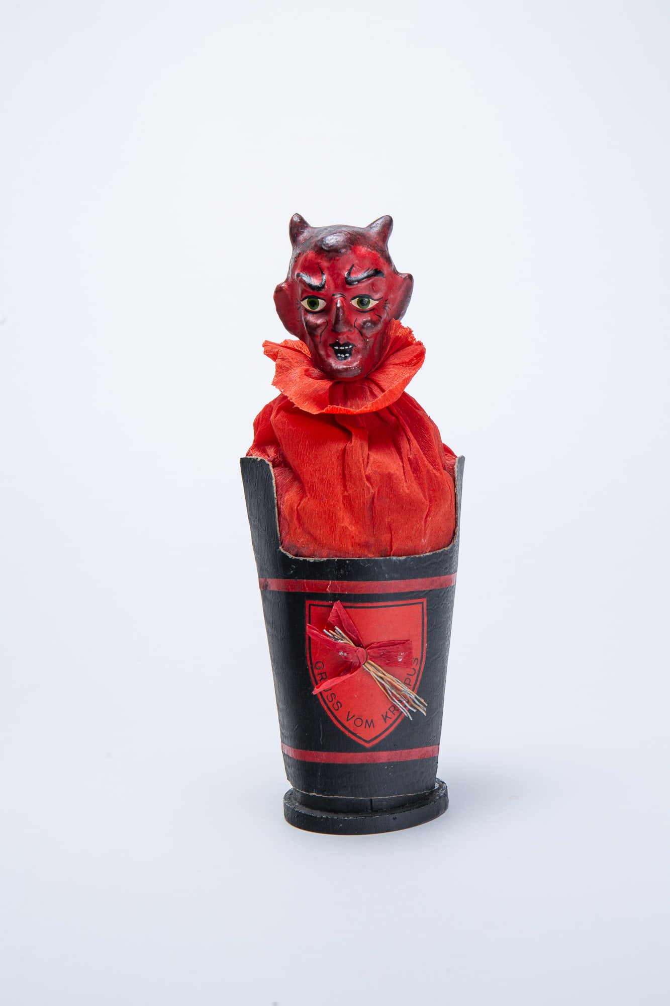 GRUSS VOM KRAMPUS CANDY CONTAINER.: GRUSS VOM KRAMPUS CANDY CONTAINER. Germany, early 20th Century. Candy container depicting a devil-like Krampus with a composition head, popping out of a black-labeled bucket. 8.5"h. 3.5"w. Provenance: