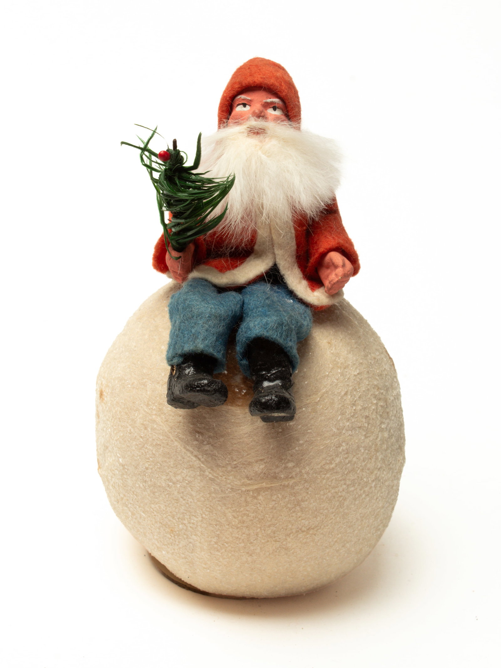 SANTA SITTING ON A SNOWBALL CANDY CONTAINER.: SANTA SITTING ON A SNOWBALL CANDY CONTAINER. Germany, early 20th Century. A Santa with a rabbit beard, wearing a red coat with white trim, blue felt pants, holding a feather tree sprig in his right