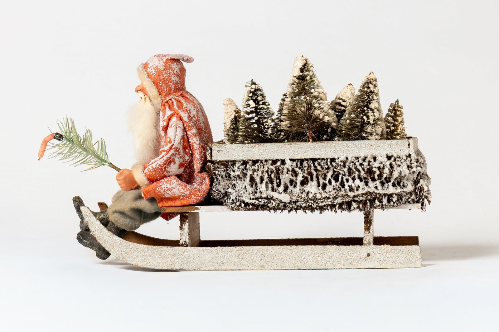 SANTA ON A LONG WOODEN SLEIGH.: SANTA ON A LONG WOODEN SLEIGH. Germany, early 20th Century. Santa wearing a snow-covered red felt coat with white trim, blue felt pants, black boots, with a painted composition face, and rabbit fur be