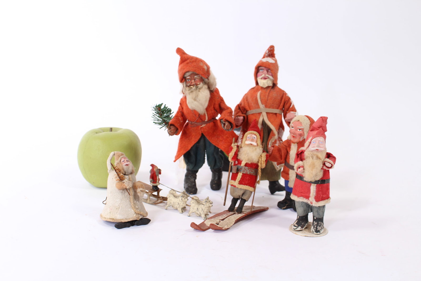 SEVEN SANTA CLAUS FIGURES.: SEVEN SANTA CLAUS FIGURES. German and American, early 20th Century. Of various sizes. Five standing Santas wearing red coats with hoods as well as painted composition faces and hands. One on skis