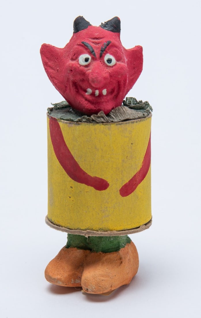 DEVIL'S HEAD HALLOWEEN CANDY CONTAINER.: DEVIL'S HEAD HALLOWEEN CANDY CONTAINER. Germany, 20th Century. Depicting a red devil with composition head and original composition feet; having a cylindrical cardboard body; 3.5"h. 1.5"w.