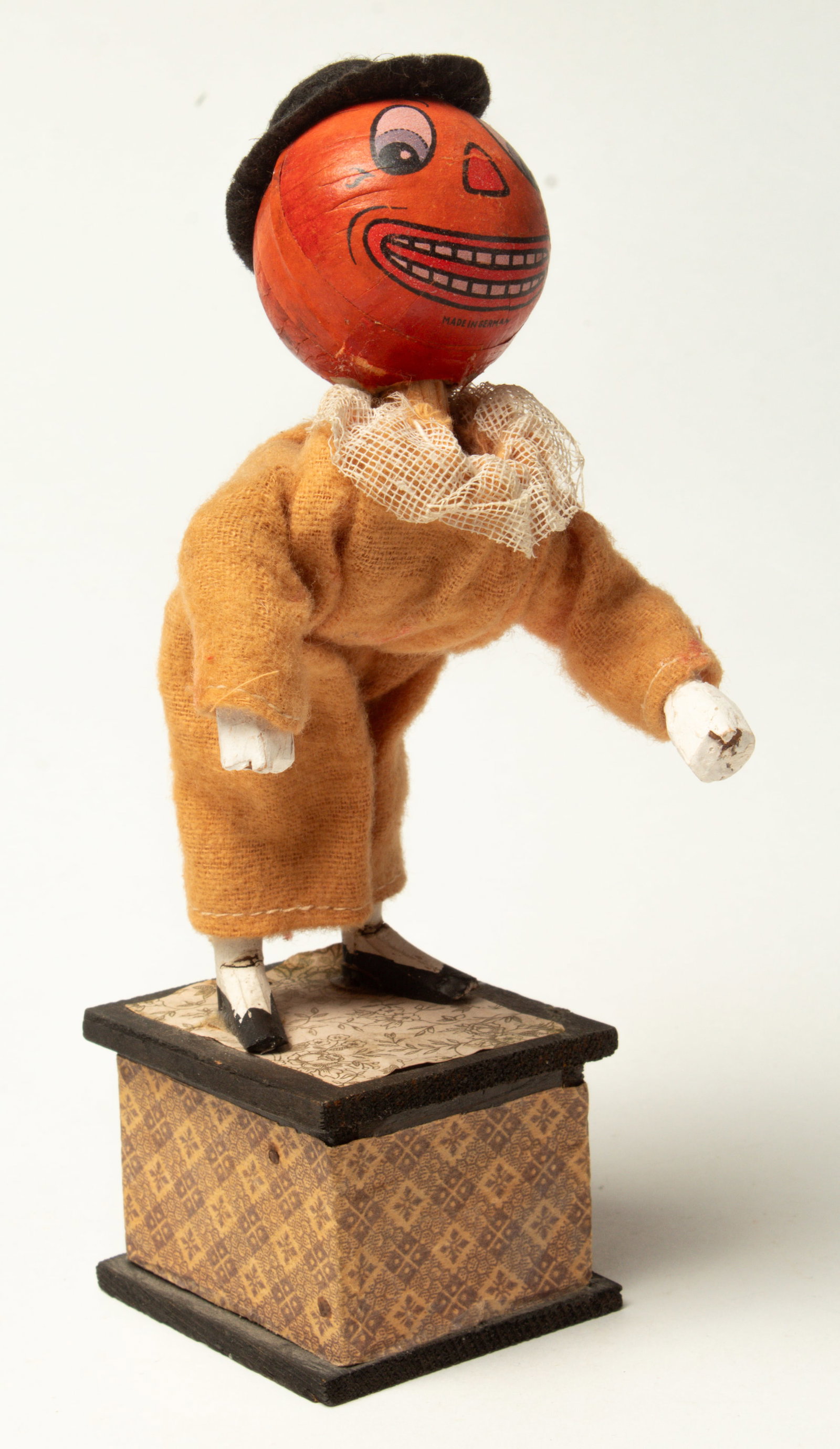 PUMPKIN MAN TWISTER ON PLATFORM.: PUMPKIN MAN TWISTER ON PLATFORM. Germany, early 20th Century. A standing pumpkin man on a paper-covered platform. He wears a black felt hat and a suit with a gauze collar. When the lever is pressed,