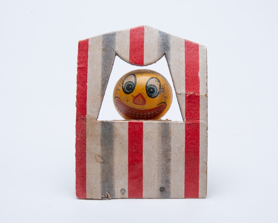PUPPET SHOW PUMPKIN HALLOWEEN SQUEAKER TOY.: PUPPET SHOW PUMPKIN HALLOWEEN SQUEAKER TOY. Germany, 20th Century. Featuring a cardboard pumpkin with expressive facial features within a white tent with red and blue stripes; pumpkin goes up and