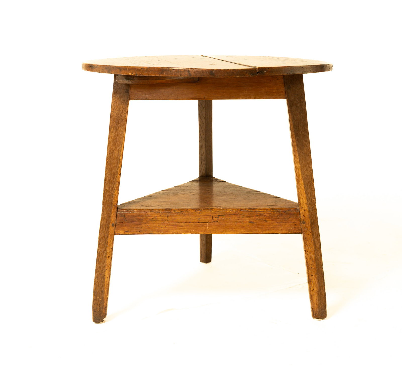 CRICKET TABLE IN PINE AND OAK.: CRICKET TABLE IN PINE AND OAK. English, late 18th Century. Round two-board top, triangular base with lower shelf and pegged construction. 28"h. 28.25"d.