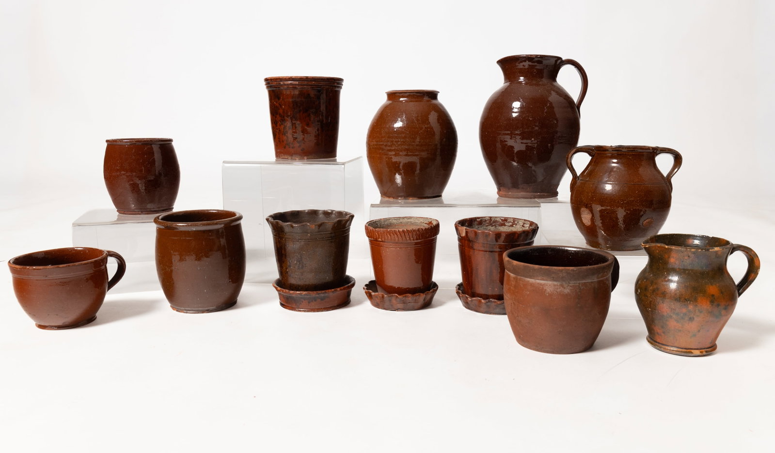 TWELVE REDWARE ITEMS.: TWELVE REDWARE ITEMS. American, 19th Century. J.H. Owen pitcher with applied handle and green and orange mottled glaze, 5.75"h. A high glaze bulbous pitcher, 10.5"h. Two single-handled bowls, 4.75"h