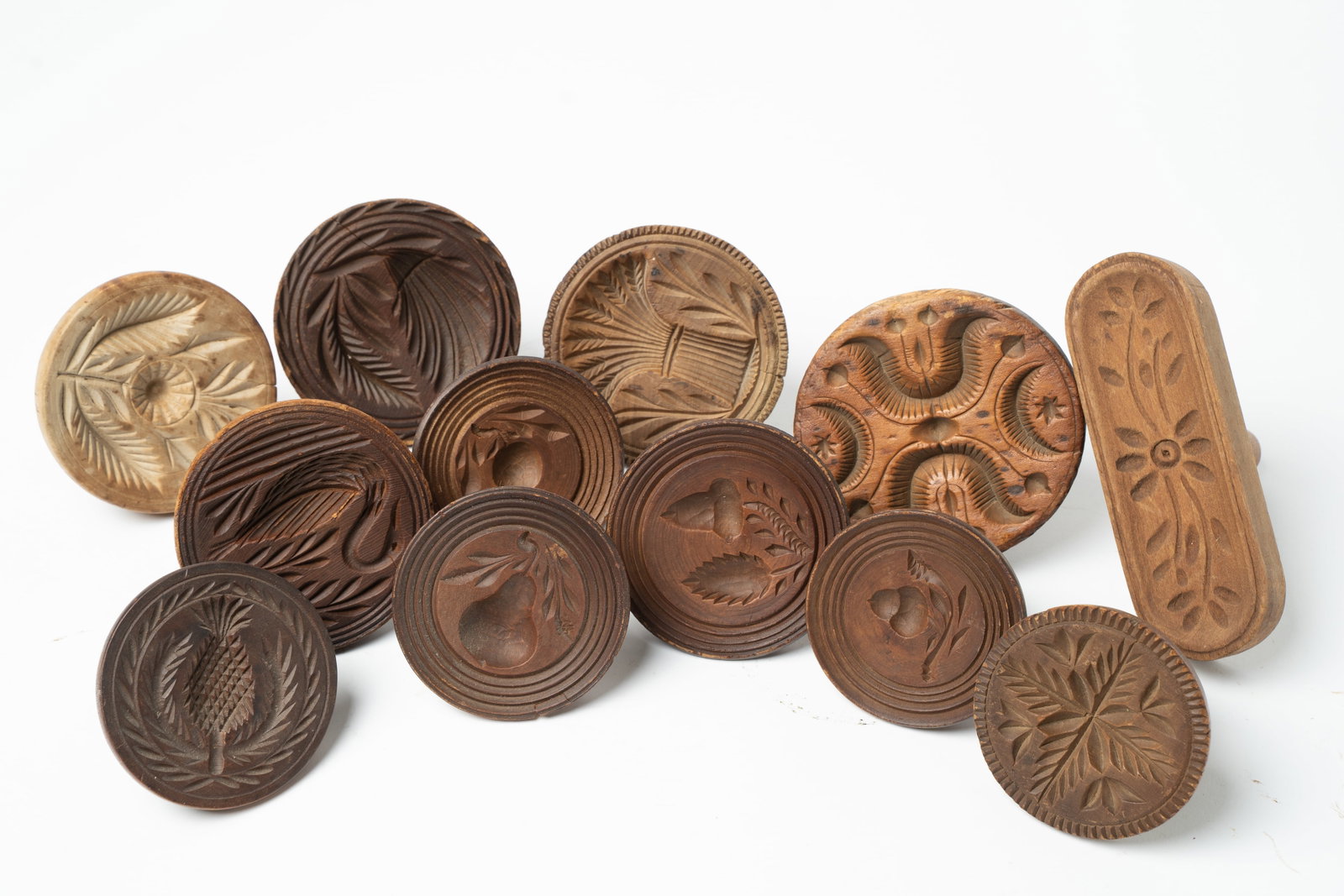TWELVE CARVED BUTTER PRINTS.: TWELVE CARVED BUTTER PRINTS. American, mid- 19th Century. Ten are turned with knob handles, one is turned with a cylindrical handle, and one is lozenge shaped. Prints include: sheaf of wheat, swan,