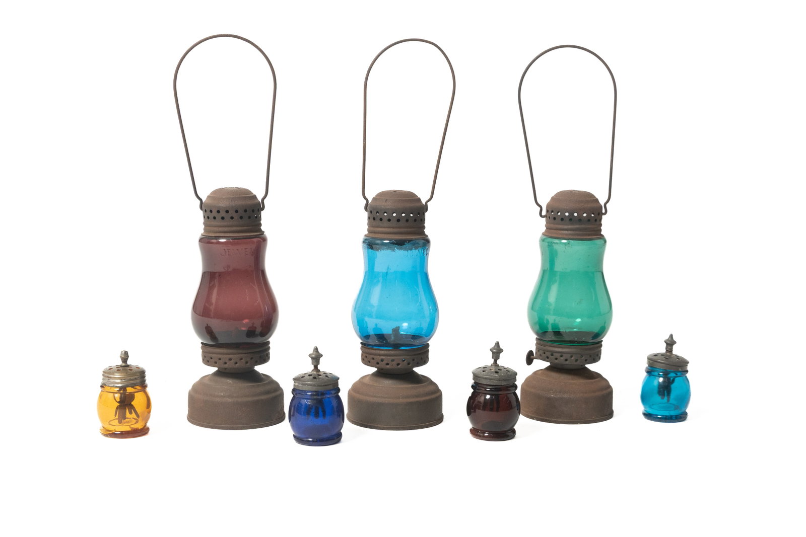 FOUR CHRISTMAS SALTS AND THREE JEWEL SKATER'S LAMPS.: FOUR CHRISTMAS SALTS AND THREE JEWEL SKATER'S LAMPS. American, late 19th or early 20th Century. Four polychrome short-barreled salt shakers in amber, cobalt, amethyst, and peacock blue with period lid