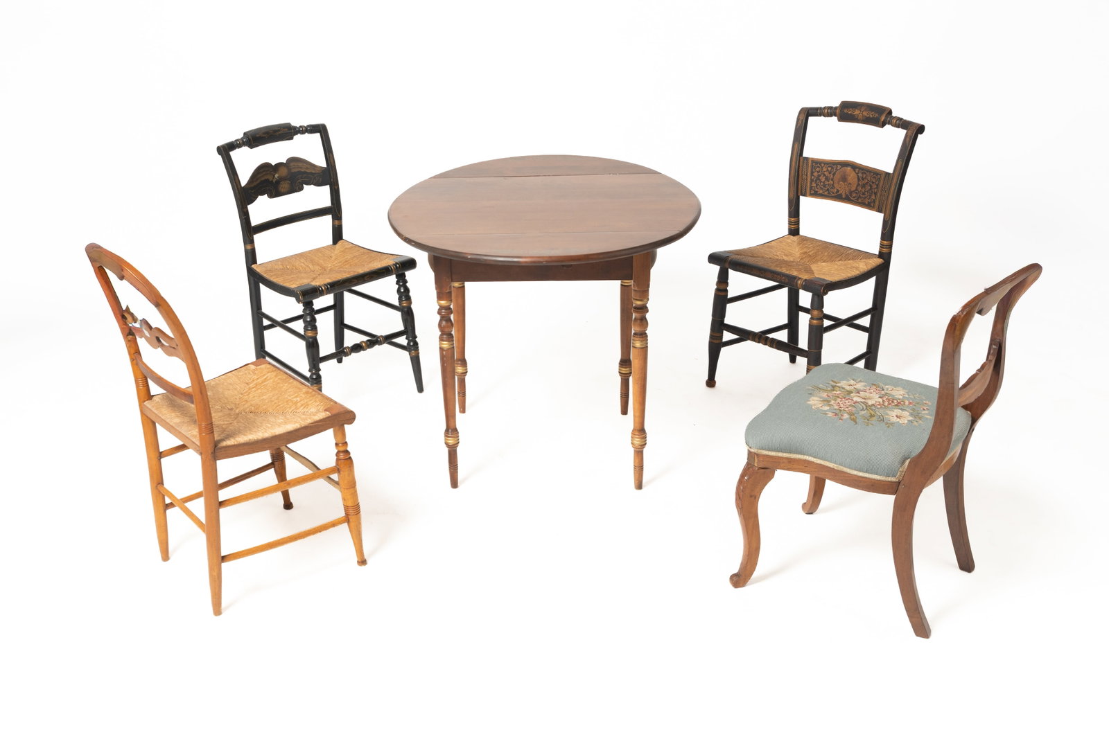 L. HITCHCOCK (CONNECTICUT) SHEARTON STYLE DROP-LEAF TABLE AND FOUR CHAIRS.: L. HITCHCOCK (CONNECTICUT) SHEARTON STYLE DROP-LEAF TABLE AND FOUR CHAIRS. American, 20th Century. Mixed wood. A maple oval drop-leaf table with stenciled floral designs, turned legs, and signed