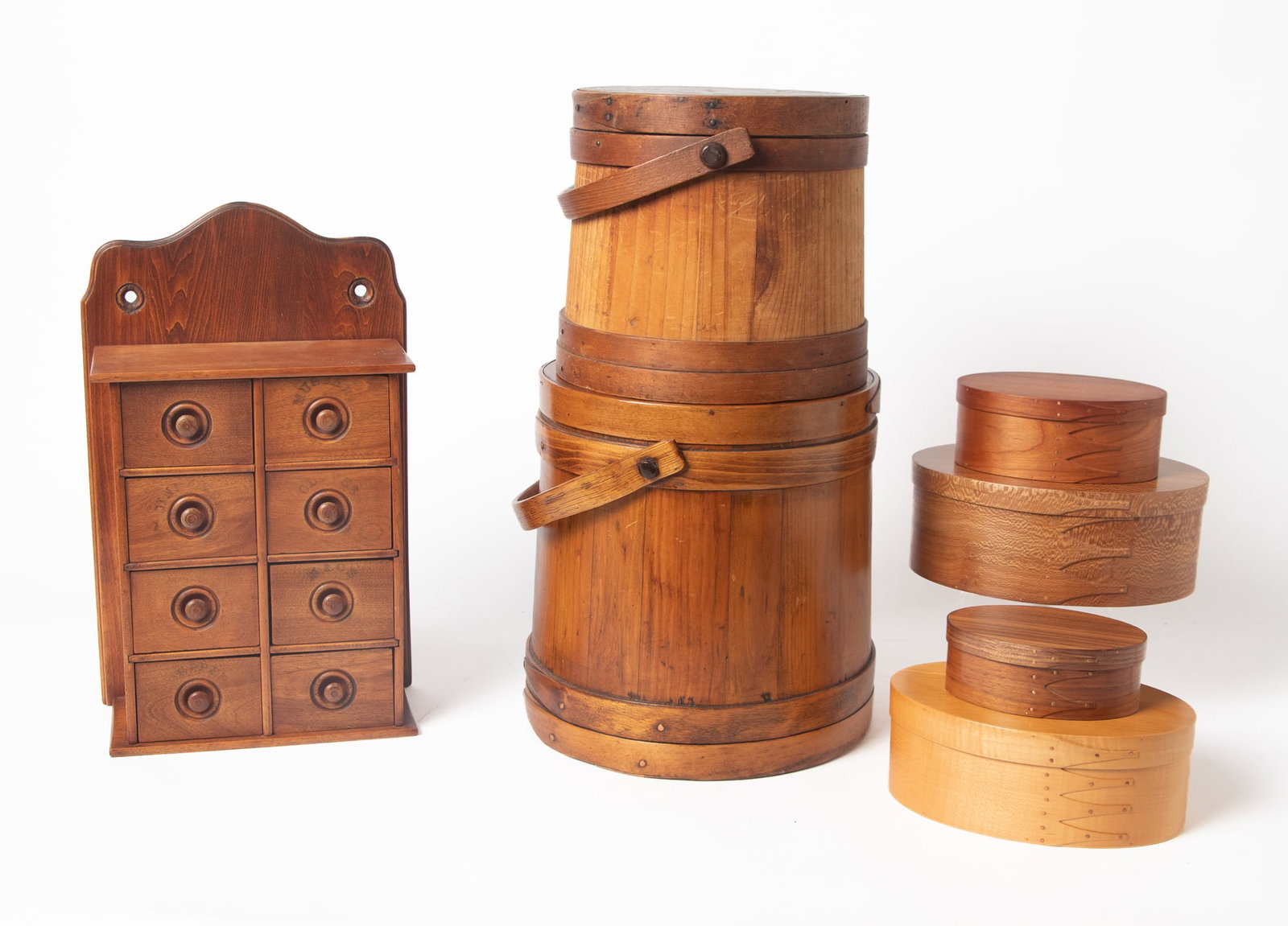SEVEN WOODEN ITEMS.: SEVEN WOODEN ITEMS. American, 19th and 20th Century. Two pine, stave-constructed firkins with bale handles, 12"h. and 9.5"h.; an eight-drawer hanging spice box, shaped back, recessed turned knobs and
