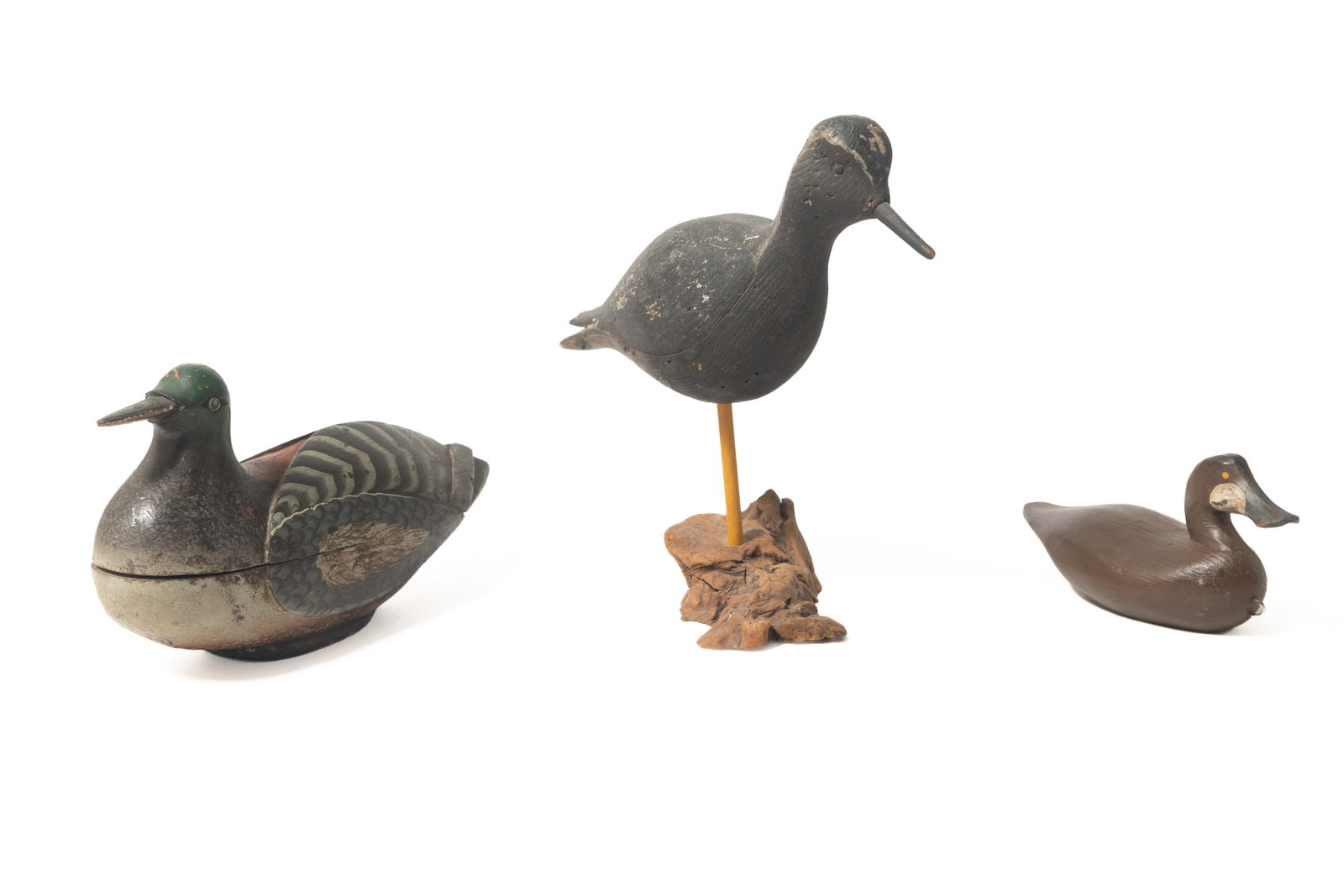 THREE CARVED AND PAINTED BIRDS.: THREE CARVED AND PAINTED BIRDS. 20th Century. A carved and painted black-bellied Plover mounted on a wooden freeform base, 8.75"h., a diminutive example of a duck in brown paint with stamp on