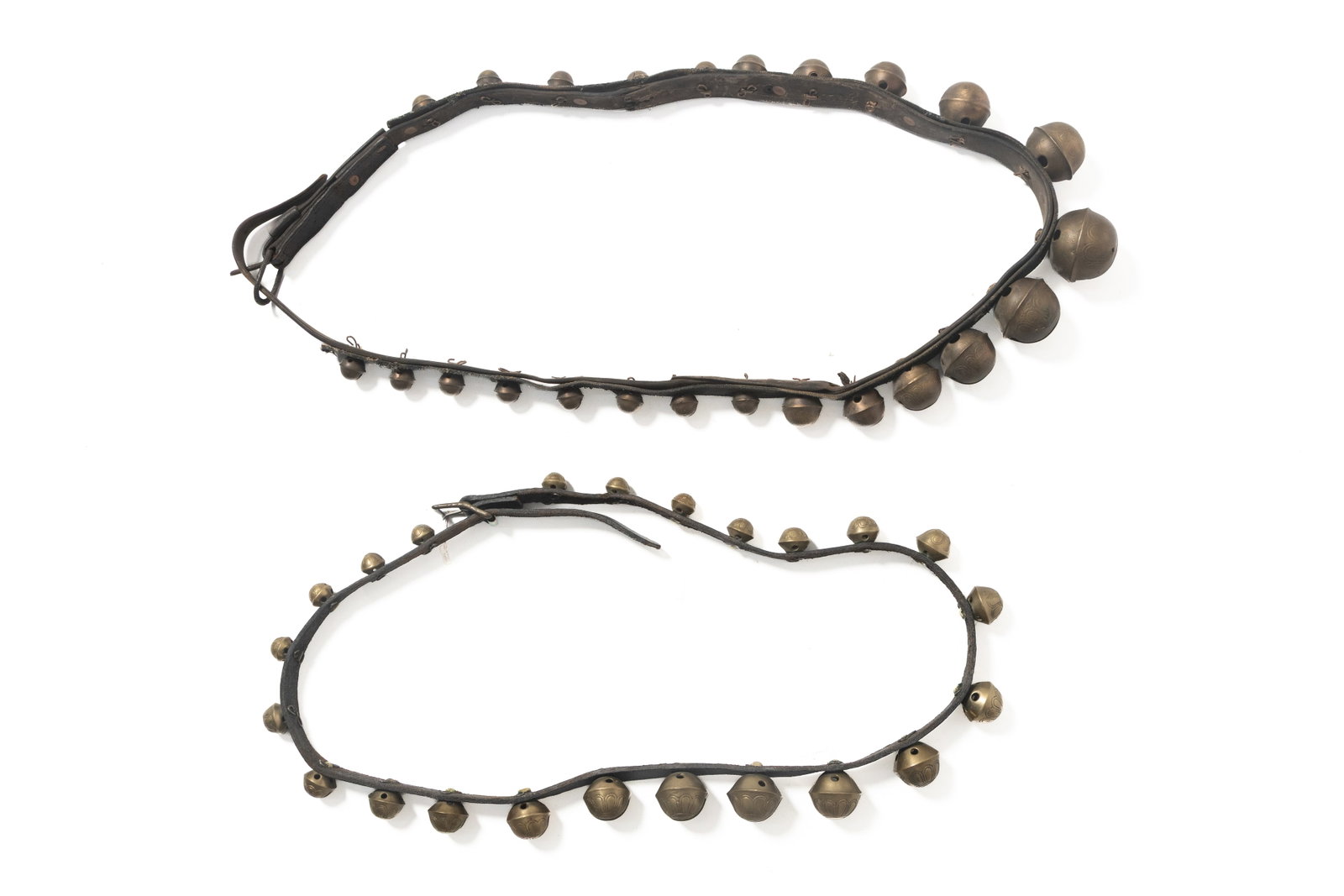 TWO SETS OF GRADUATED BRASS SLEIGH BELLS ON LEATHER STRAPS.: TWO SETS OF GRADUATED BRASS SLEIGH BELLS ON LEATHER STRAPS. American, 19th Century. Two sets of brass sleigh bells on leather straps; one with 24 bells, 78"l. and one with 23 bells, 79"l. Provenance: