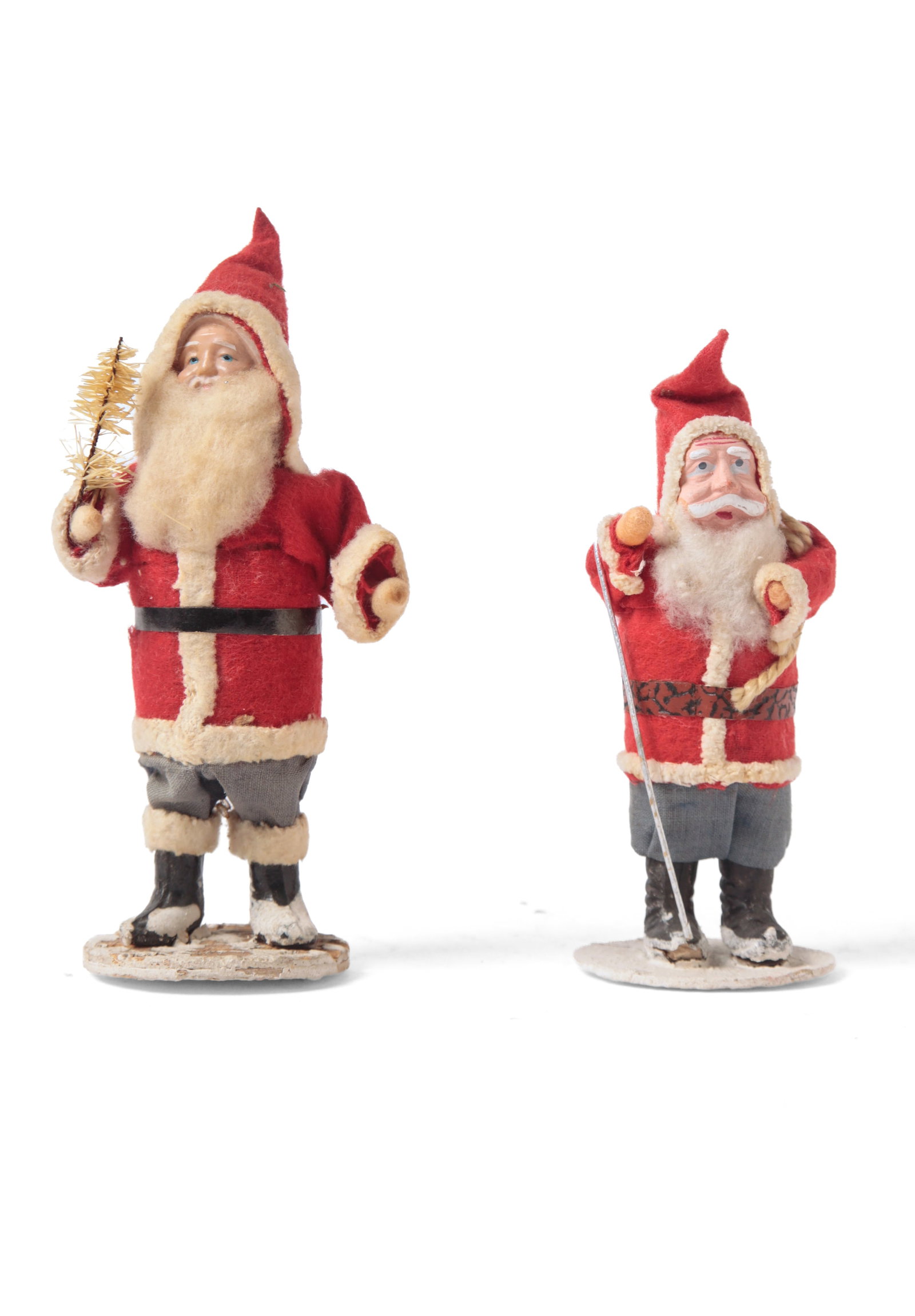 TWO JAPANESE STANDING SANTA FIGURES.: TWO JAPANESE STANDING SANTA FIGURES. Early 20th Century. A standing Santa figure holding a white bottle brush tree, wearing a red-hooded coat, blue pants, and black boots, with a cotton beard and