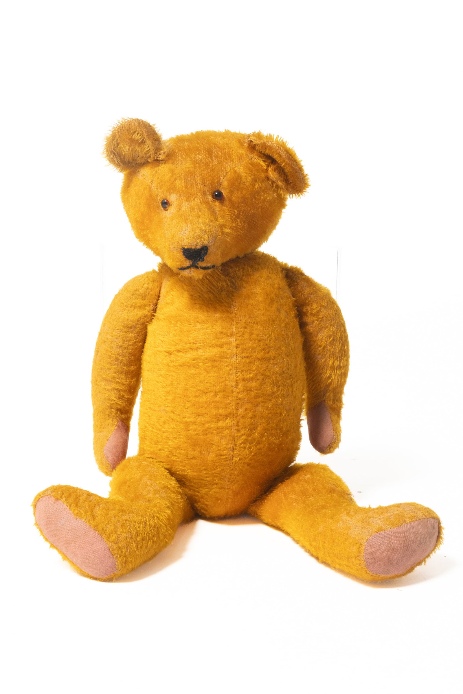 LARGE STRAW-STUFFED MOHAIR TEDDY BEAR.: LARGE STRAW-STUFFED MOHAIR TEDDY BEAR. German, early 20th Century. Fully articulated with bright gold or orange mohair, glass eyes, sewn nose and mouth, and pink felt pads. 27.5"h. Provenance: Nancy G