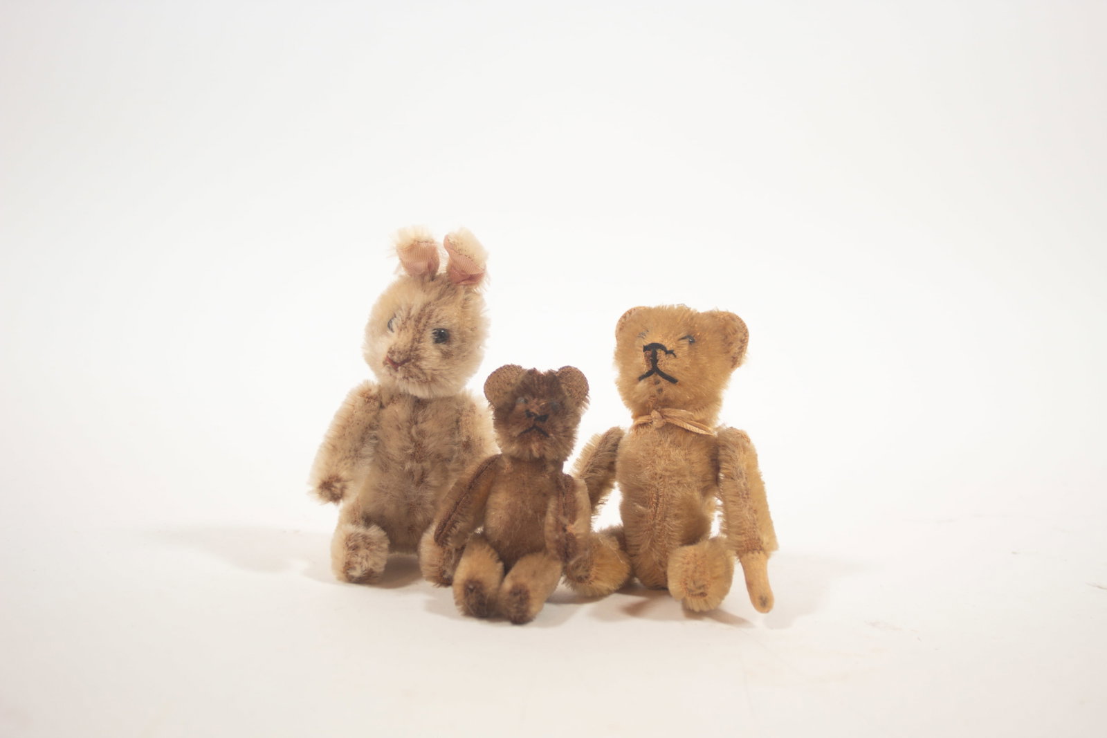 THREE DIMINUTIVE SCHUCO MOHAIR ANIMALS.: THREE DIMINUTIVE SCHUCO MOHAIR ANIMALS. German, early 20th Century. A tumbling bear in golden mohair, 5"h., a rabbit perfume that is fully-jointed with glass eyes, a red sewn nose and mouth, and a rem