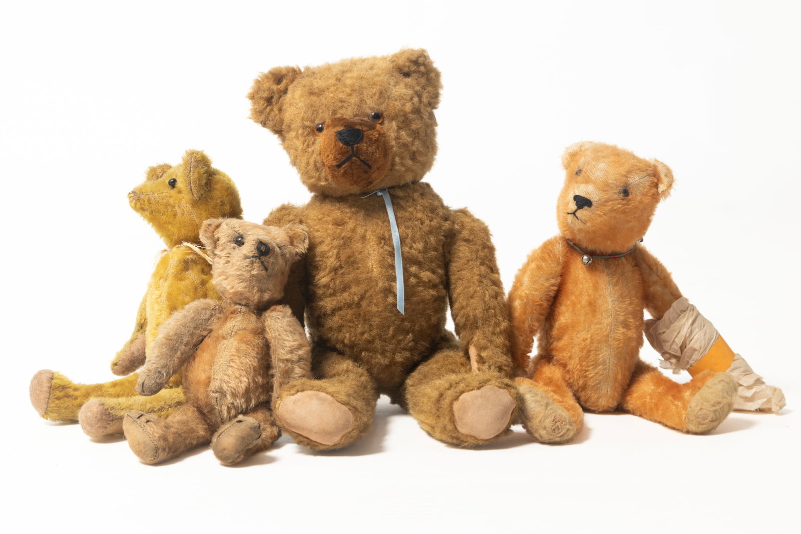 FOUR FULLY-JOINTED MOHAIR TEDDY BEARS.: FOUR FULLY-JOINTED MOHAIR TEDDY BEARS. German, early 20th Century. The largest with brown mohair, straw-stuffed, glass eyes, and a cotton muzzle, 18"h. A straw-stuffed bear with shoe-button eyes, stit