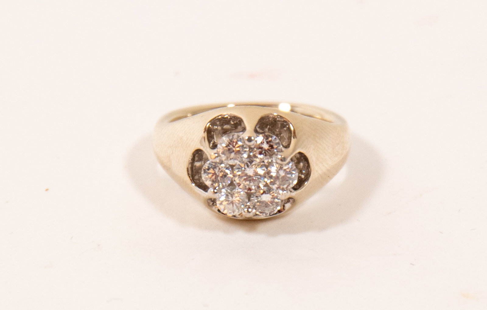 14K WHITE GOLD CLUSTER RING.: 14K WHITE GOLD CLUSTER RING. Contemporary. A thick band with scalloped prongs holding a cluster of seven round brilliant-cut diamonds, approximately 1 ctw., size 7.25. Approximatley 9.5g.