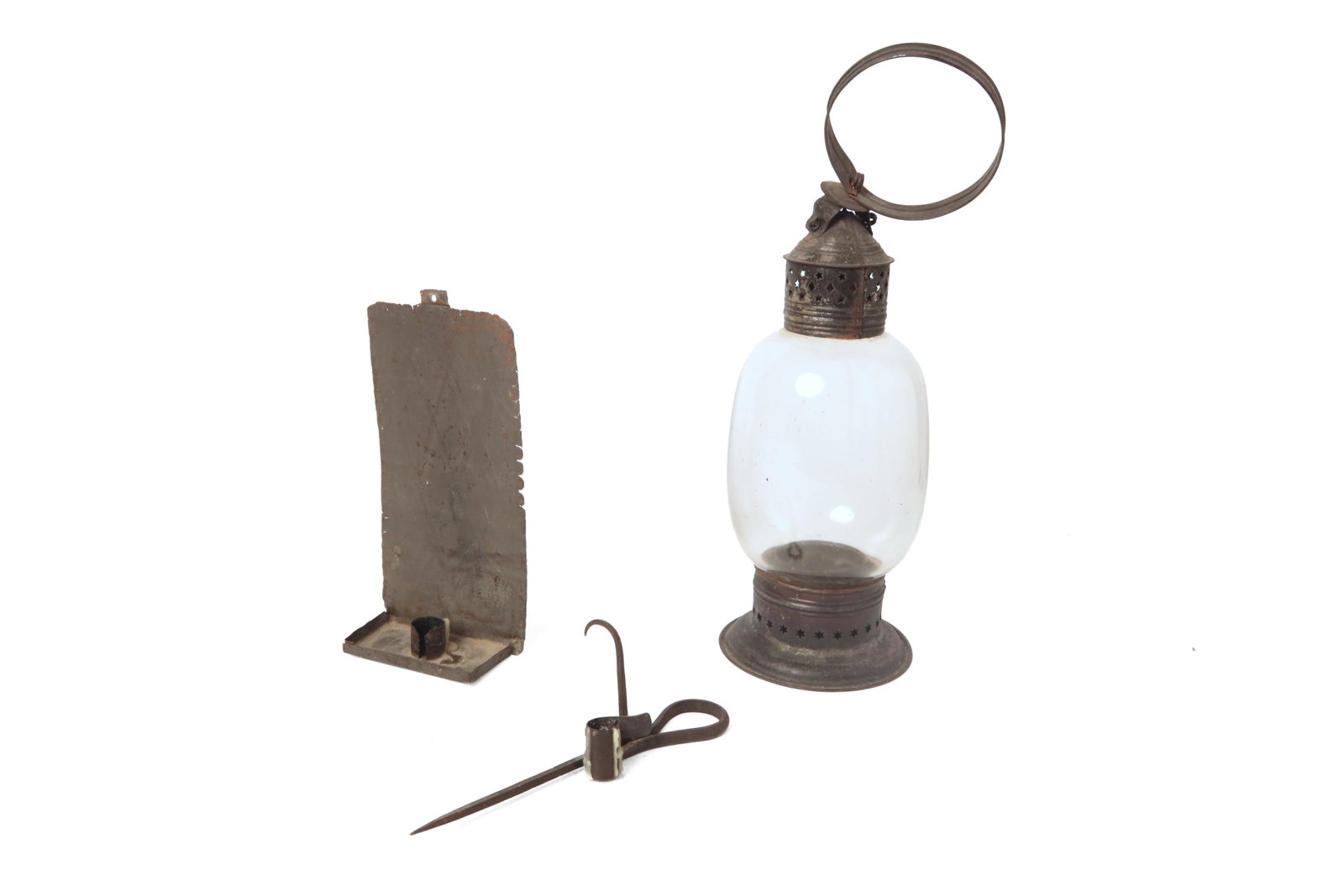 THREE EARLY LIGHTING ITEMS.: THREE EARLY LIGHTING ITEMS. American, first half 19th Century. A tin lantern with blown, clear glass lens, ring handle, die-stamped cap, and base with stars and diamonds, 17.75"h., a forged iron