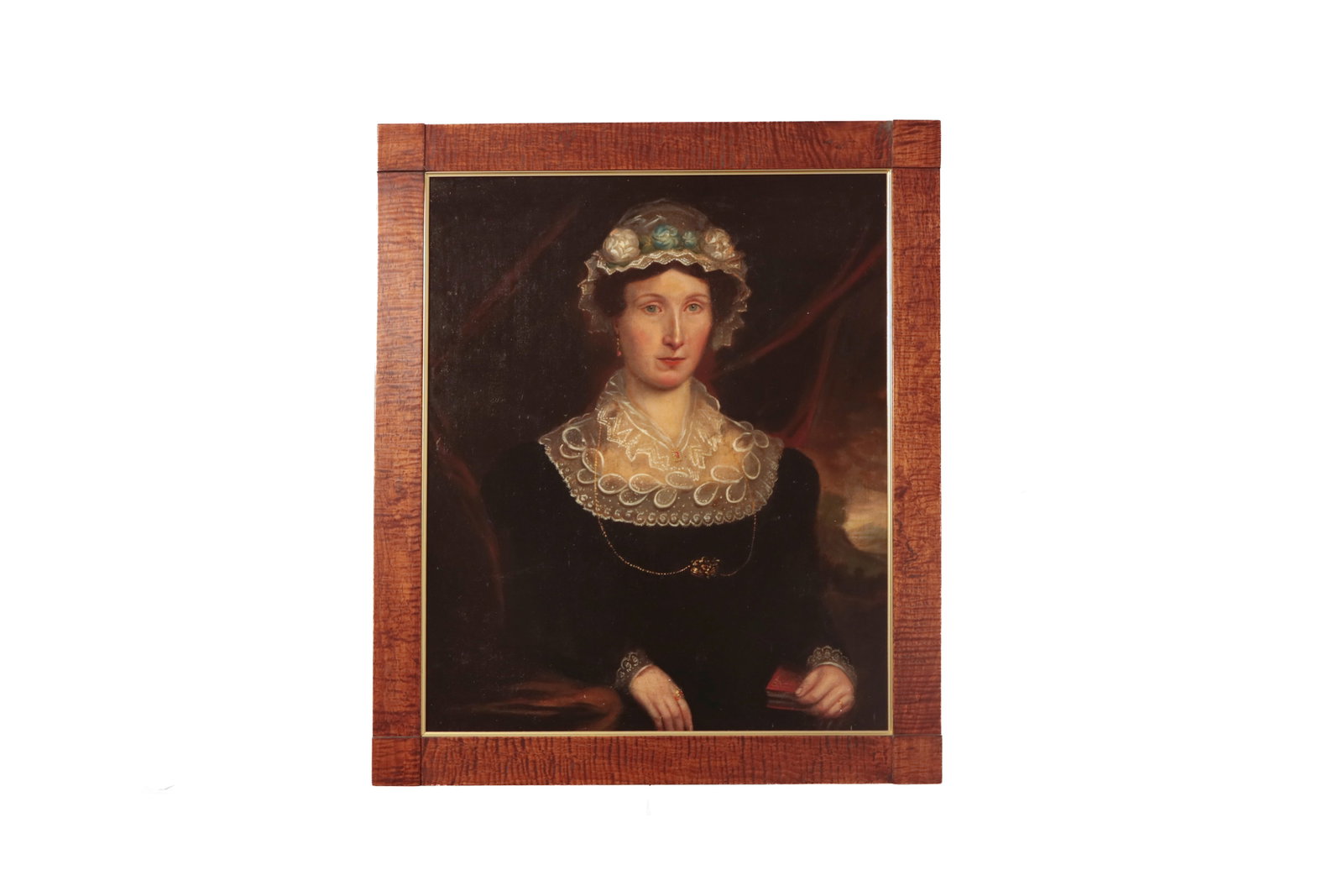 AMERICAN SCHOOL PORTRAIT OF A LADY IN A TIGER MAPLE FRAME.: AMERICAN SCHOOL PORTRAIT OF A LADY IN A TIGER MAPLE FRAME. Second quarter 19th Century. Oil on canvas. She has dark hair and pale blue eyes. She wears a floral lace cap, black dress with puffy