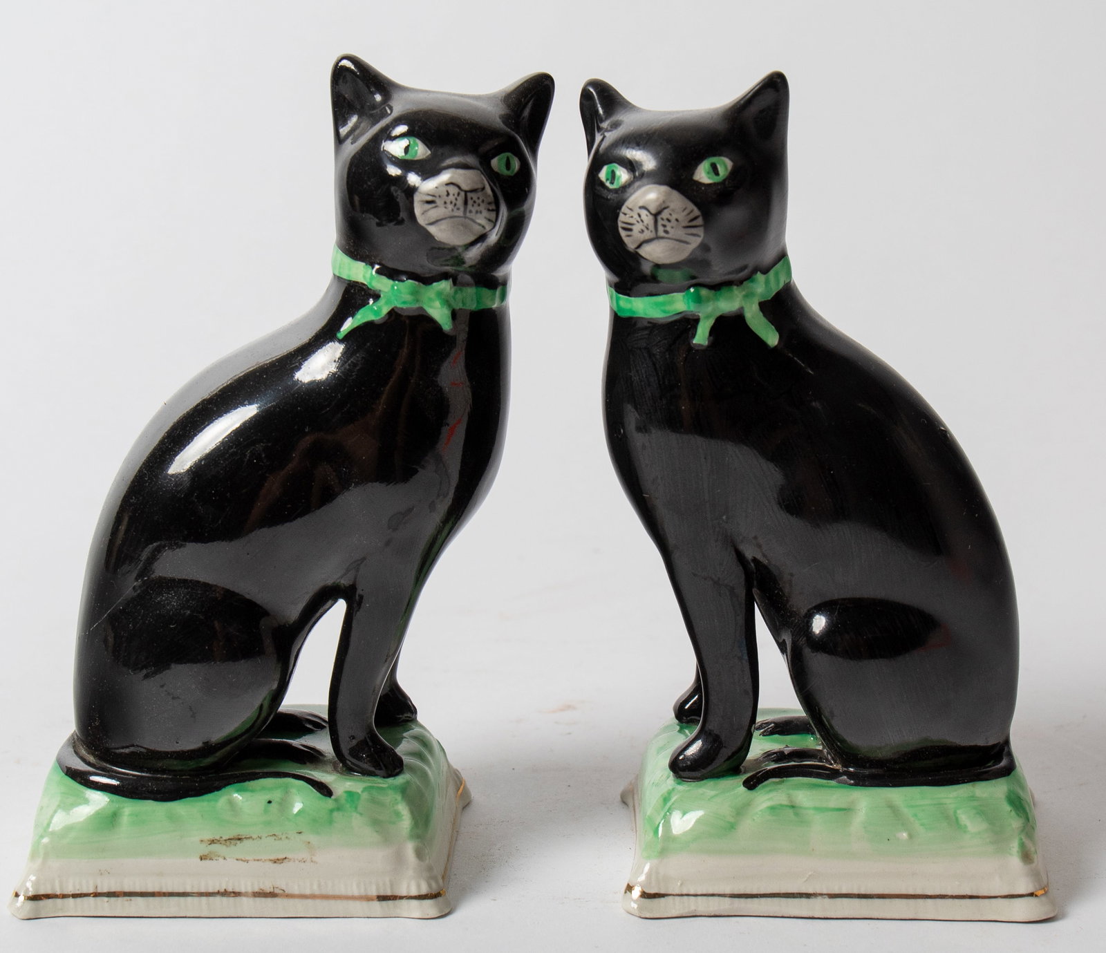 PAIR OF STAFFORDSHIRE SEATED BLACK CATS.: PAIR OF STAFFORDSHIRE SEATED BLACK CATS. English, 19th Century. With freestanding front legs; having green eyes, ribbon collars, and bases; 7"h. 3"w. 4"d. Provenance: The Lifetime Collection of the la