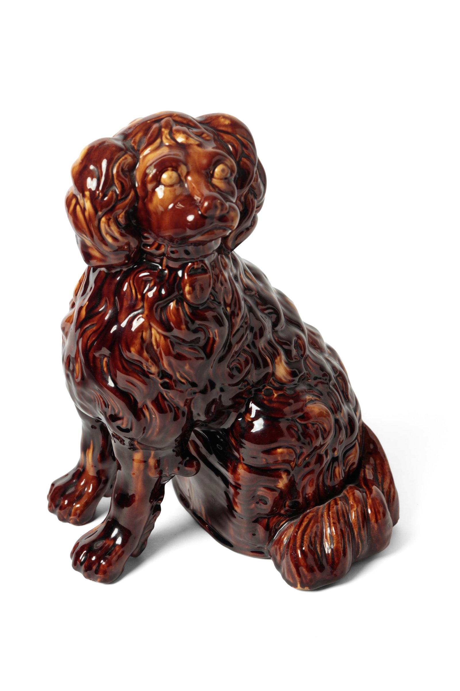 LARGE YELLOWWARE SEATED SPANIEL WITH ROCKINGHAM GLAZE.: LARGE YELLOWWARE SEATED SPANIEL WITH ROCKINGHAM GLAZE. American, 19th Century. Free-standing seated spaniel, facing sideways, with a collar and lock at its neck, a wonderfully detailed coat, hollow bo