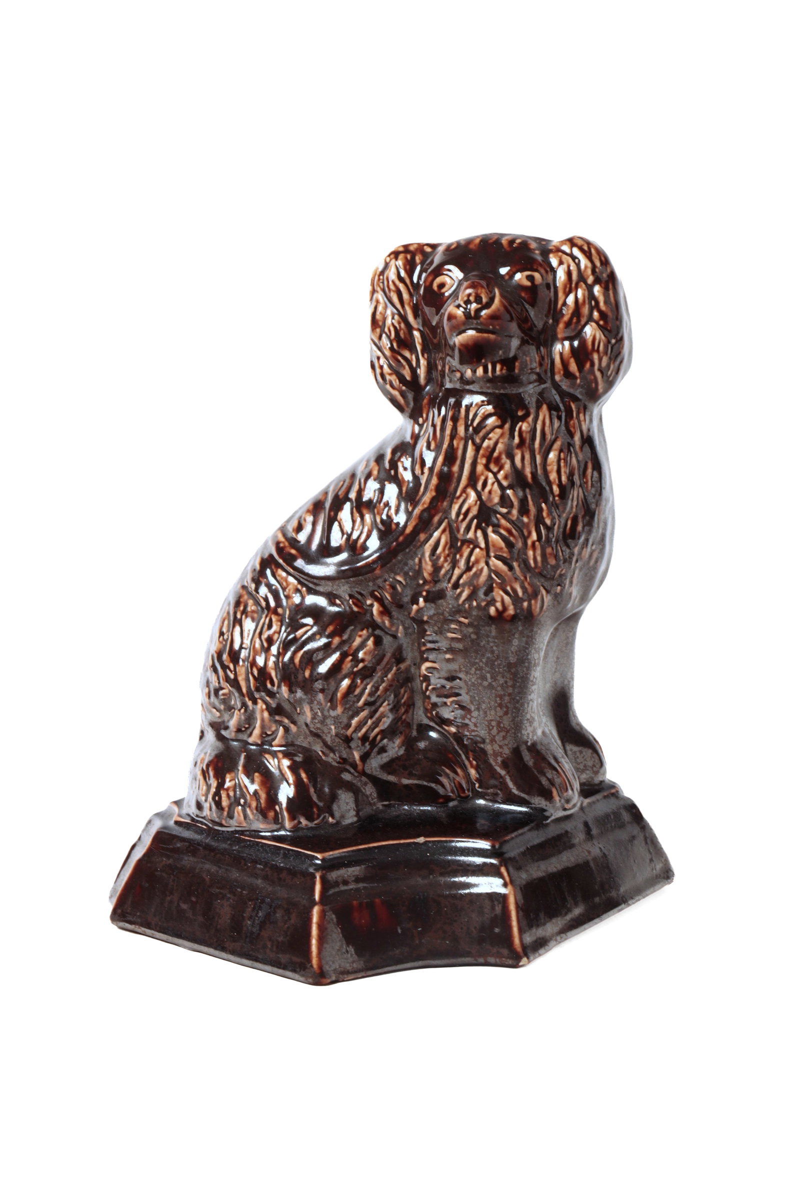 ATWATER, OHIO BUFF CLAY SEATED SPANIEL IN BROWN GLAZE.: ATWATER, OHIO BUFF CLAY SEATED SPANIEL IN BROWN GLAZE. American, 19th Century. Seated spaniel with incised face, textured coat, on a shaped base with clipped corners. 9.5"h. 8"w. Provenance: Nancy