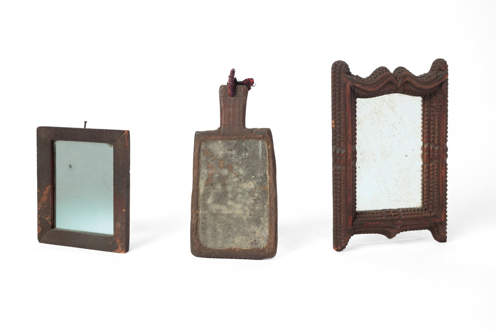 THREE FRAMED MIRRORS.: THREE FRAMED MIRRORS. American, 19th or 20th Century. A fragment mirror, set into a carved piece of wood with a hand hold, 8.25"l. 4"w., a rectangular mirror in a veneered, painted frame, 6"h. 5"w.,