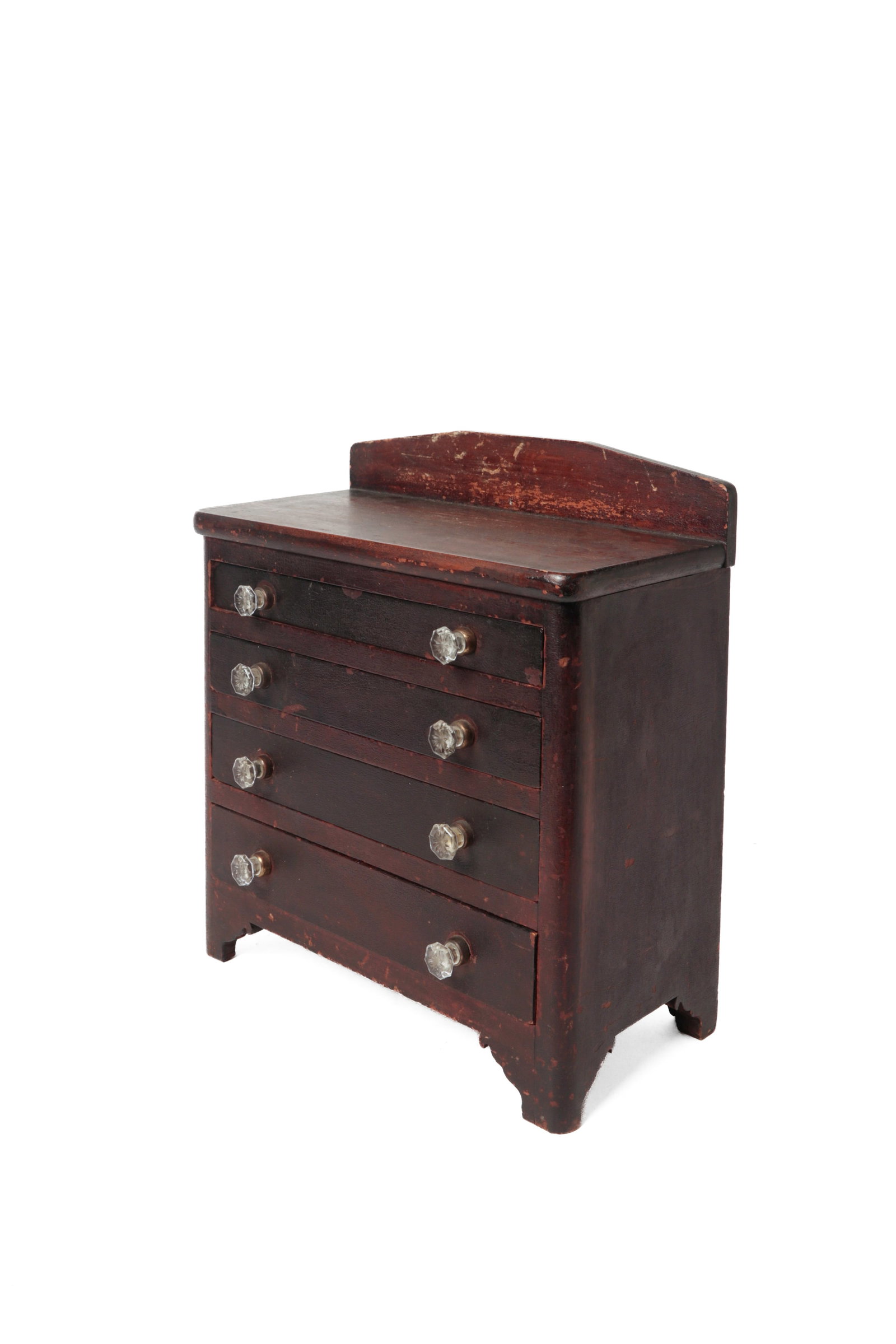 MINIATURE FOUR-DRAWER CHEST.: MINIATURE FOUR-DRAWER CHEST. American, 19th Century. One-board rectangular top with arched gallery, solid ends, four graduated dovetailed drawers with glass pulls, simple cut-out feet, and dark