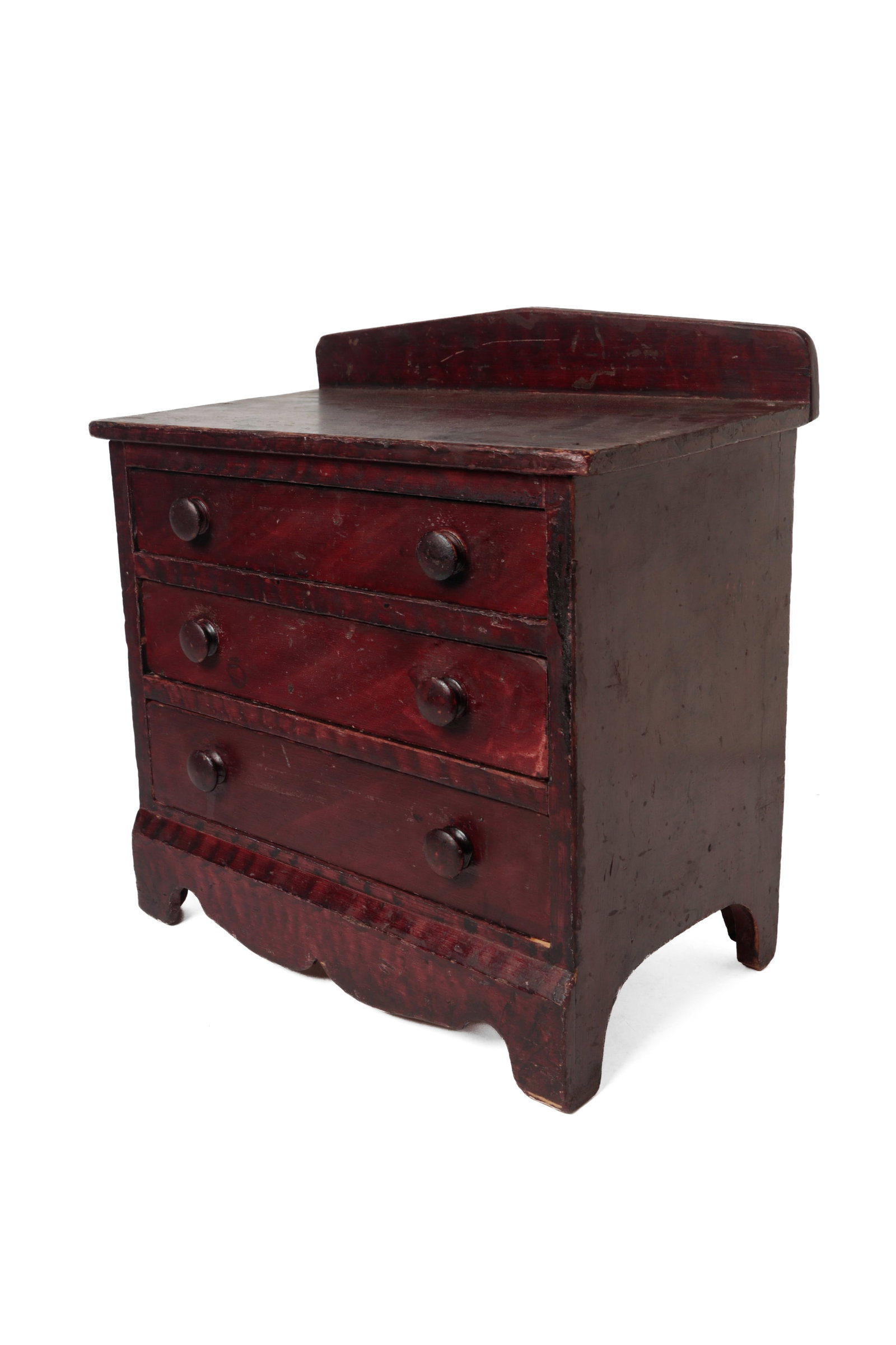MINIATURE GRAIN-PAINTED THREE-DRAWER CHEST.: MINIATURE GRAIN-PAINTED THREE-DRAWER CHEST. American, 19th or early 20th Century. Rectangular top with arched backsplash, solid ends, scalloped apron at front, high cut-out feet on sides, and three