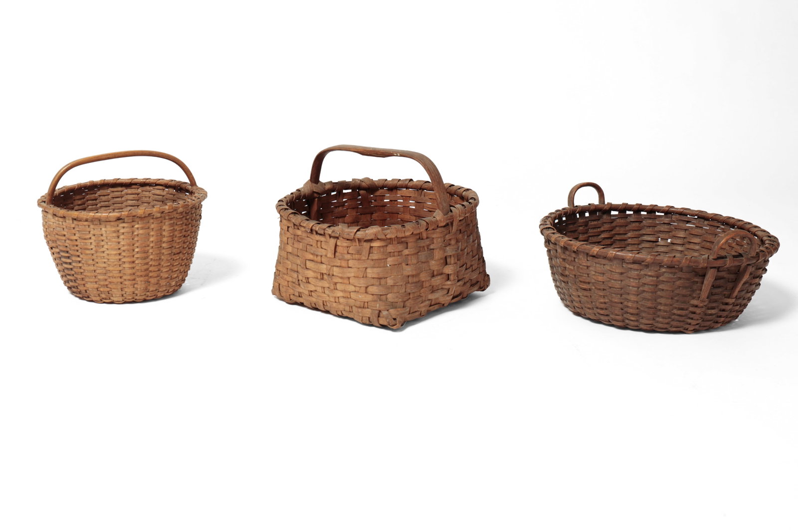 THREE BENTWOOD HANDLED BASKETS.: THREE BENTWOOD HANDLED BASKETS. American, 19th or 20th Century. Largest of circular form, tightly woven splints, pushed-up bottom, dark patina, and two handles, 6”h. Plus handles 17”w.