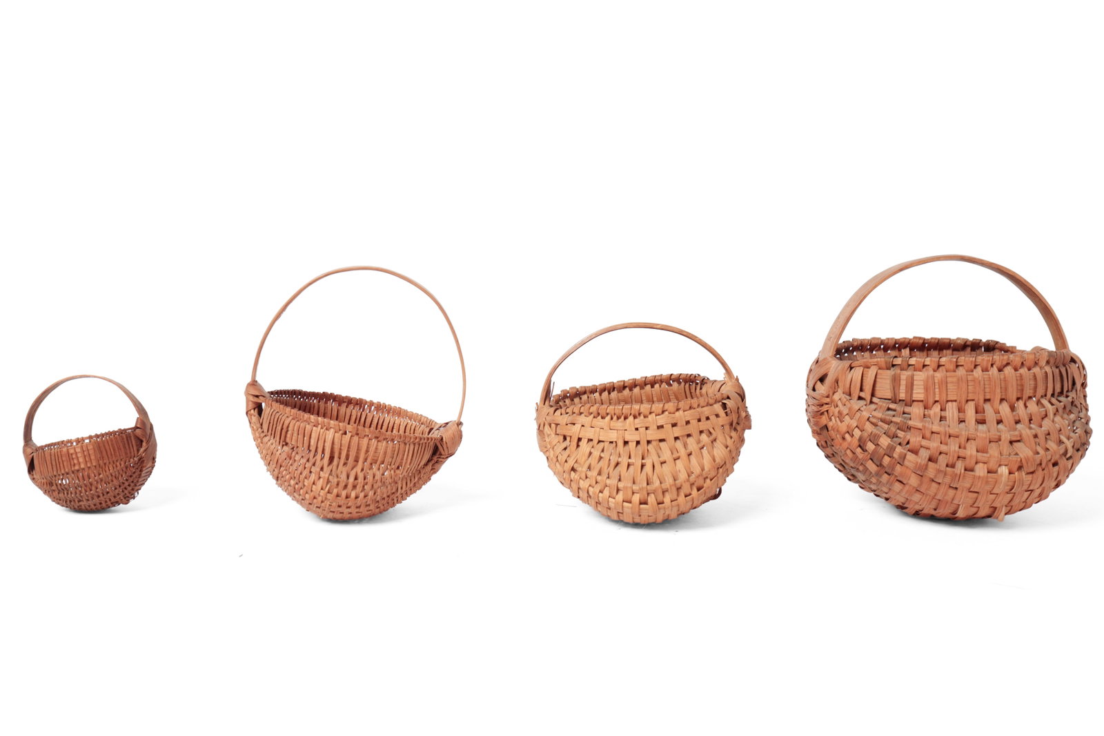 FOUR DIMINUTIVE WOVEN SPLINT BUTTOCKS BASKETS.: FOUR DIMINUTIVE WOVEN SPLINT BUTTOCKS BASKETS. American, 19th or 20th Century. Largest with tightly woven medium splints, wrapped edge, and bentwood handle signed “Kentucky”, 3.5”h.