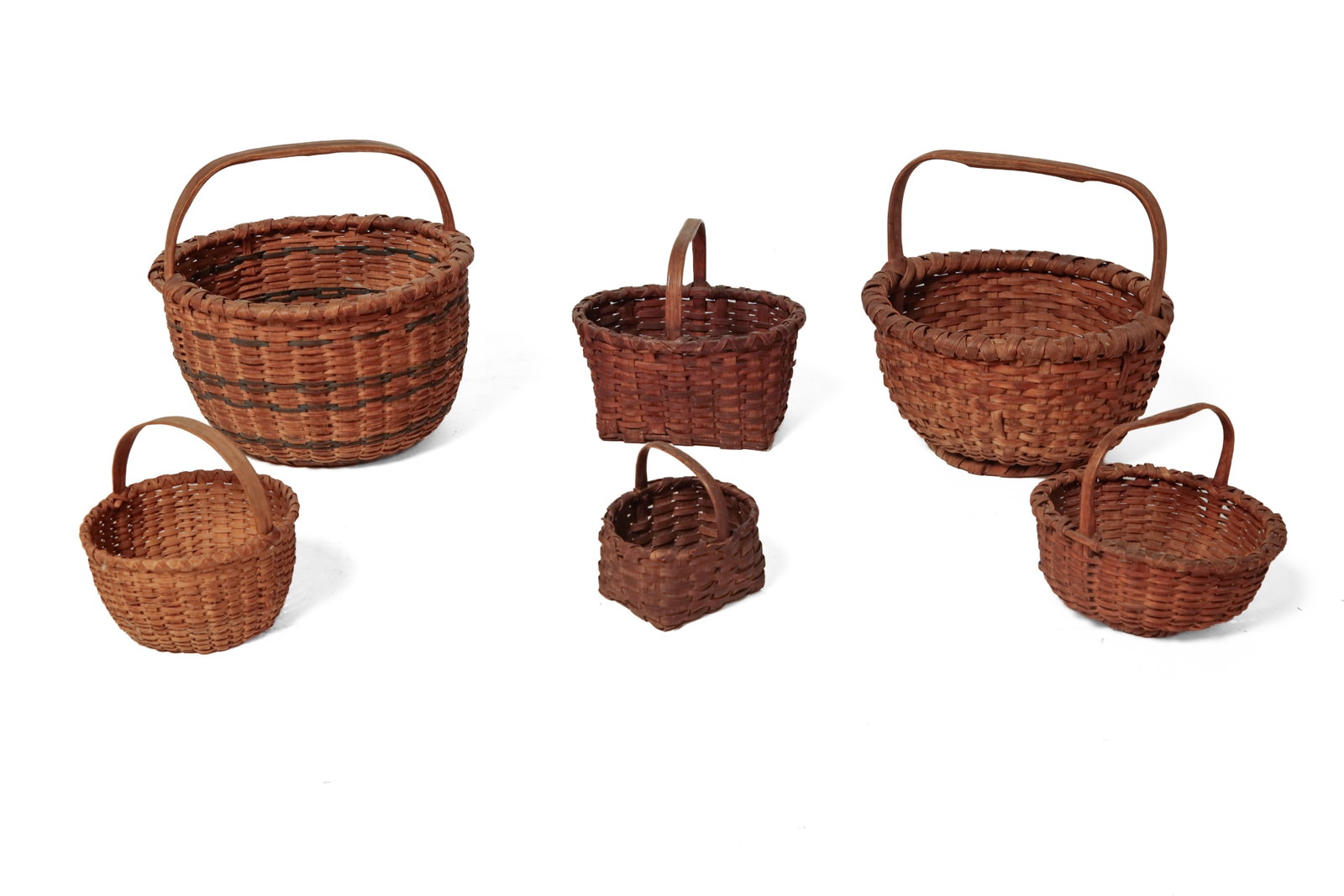 SIX HANDLED SPLINT BASKETS.: SIX HANDLED SPLINT BASKETS. American, late 19th and 20th Century. Four are round. The largest with green horizontal bands. 2.5"h. to. 7.25"h. Two have a rectangular bottom and lozenge-shaped top.