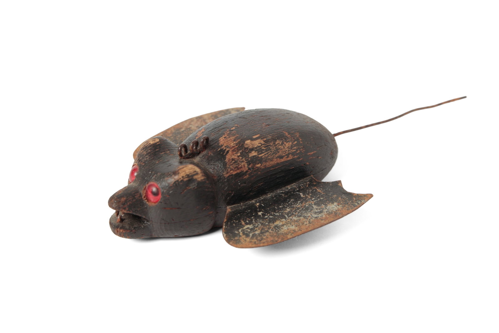FOLK ART CARVED AND PAINTED BAT ICE FISHING DECOY.: FOLK ART CARVED AND PAINTED BAT ICE FISHING DECOY. American, 20th Century. Wood and tin. Black-painted bat with a carved head and body, tin wings, red glass eyes, and the underside with an inset lead 