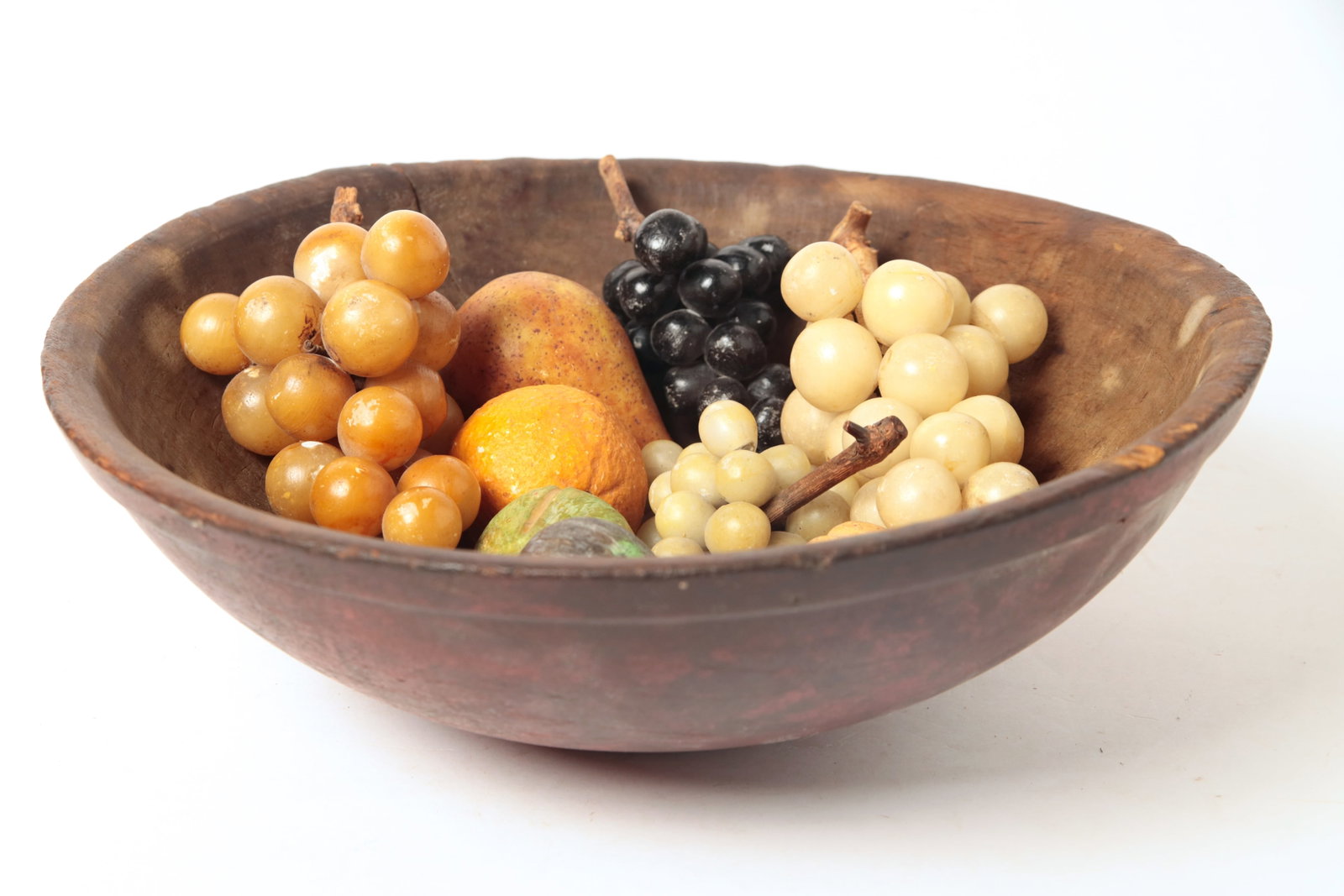 GROUP OF STONE FRUIT IN A PAINTED TURNED PINE BOWL.: GROUP OF STONE FRUIT IN A PAINTED TURNED PINE BOWL. American, 19th and 20th Century. Fruit includes bunches of grapes, pear, orange, fig, and walnut. Bowl has original red paint. Bowl, 5"h. 16.5"d.