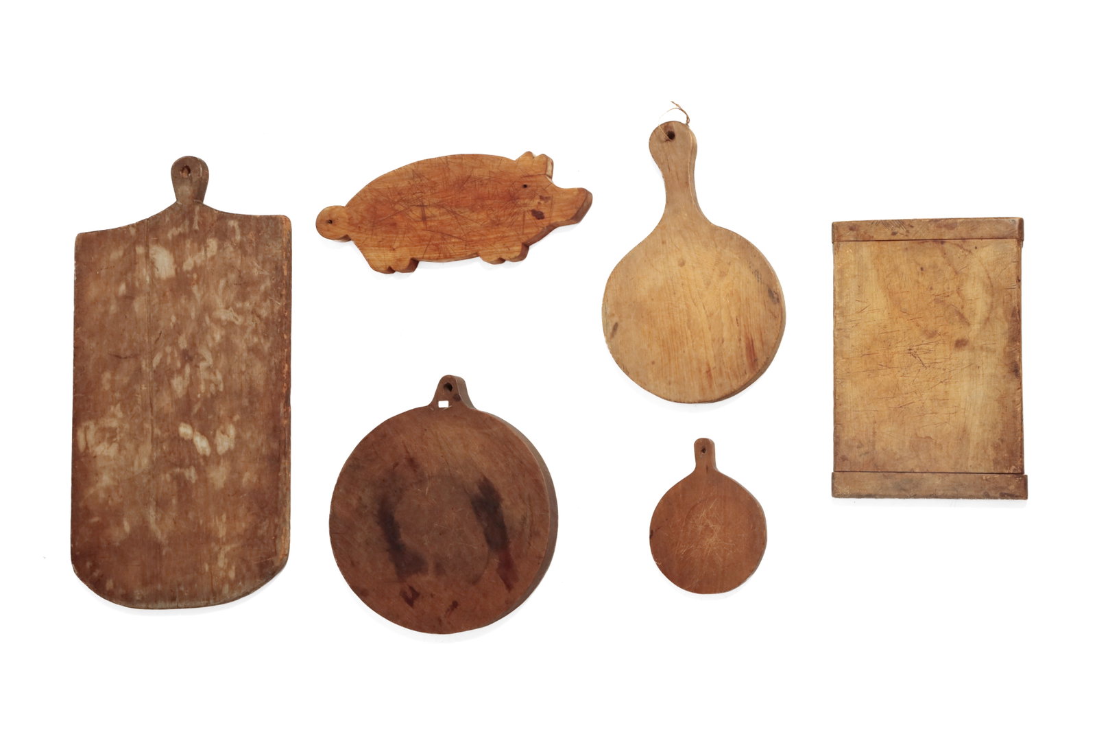 SIX WOOD CUTTING BOARDS IN VARIOUS FORMS.: SIX WOOD CUTTING BOARDS IN VARIOUS FORMS. American, 19th or early 20th Century. Mixed woods. The largest, a tombstone-shaped board with handle, 30.25"h. 14.5"w., a rectangular board with breadboard en