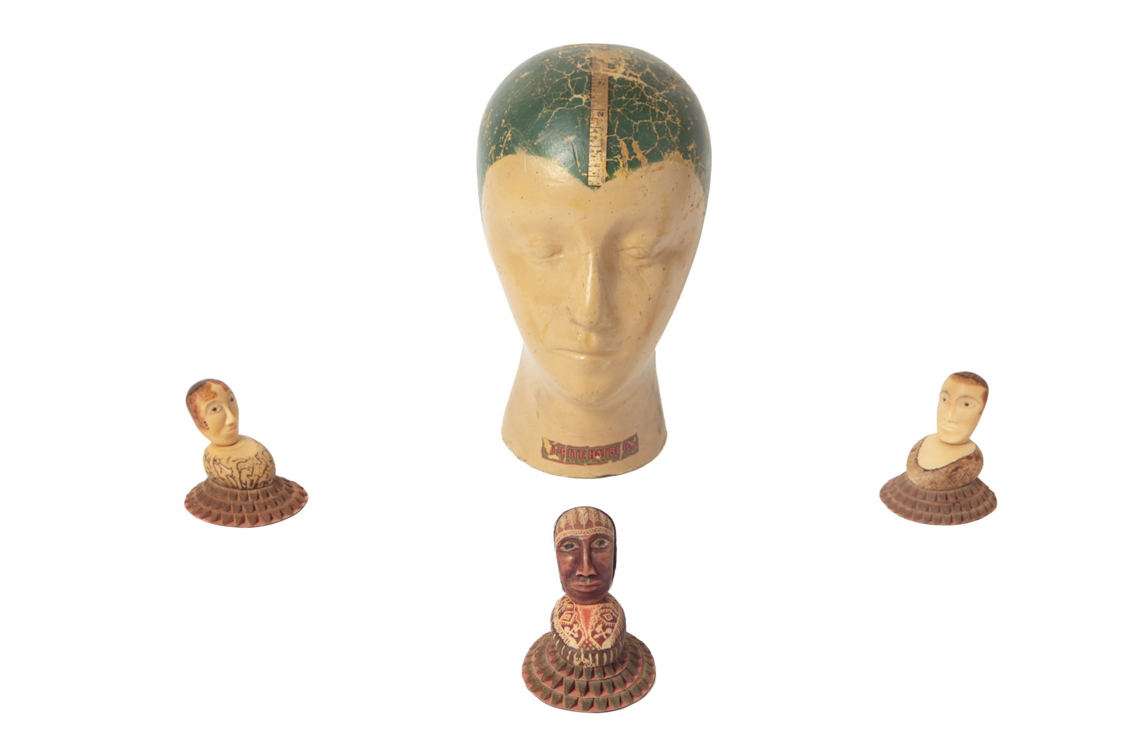 FIT-RITE HAT BLOCK MILNER'S HEAD AND THREE CARVED TAGUA BUSTS.: FIT-RITE HAT BLOCK MILNER'S HEAD AND THREE CARVED TAGUA BUSTS. American, early 20th Century. Papier-mache ladies' head form with a ruler running down and across the head, pronounced facial features,