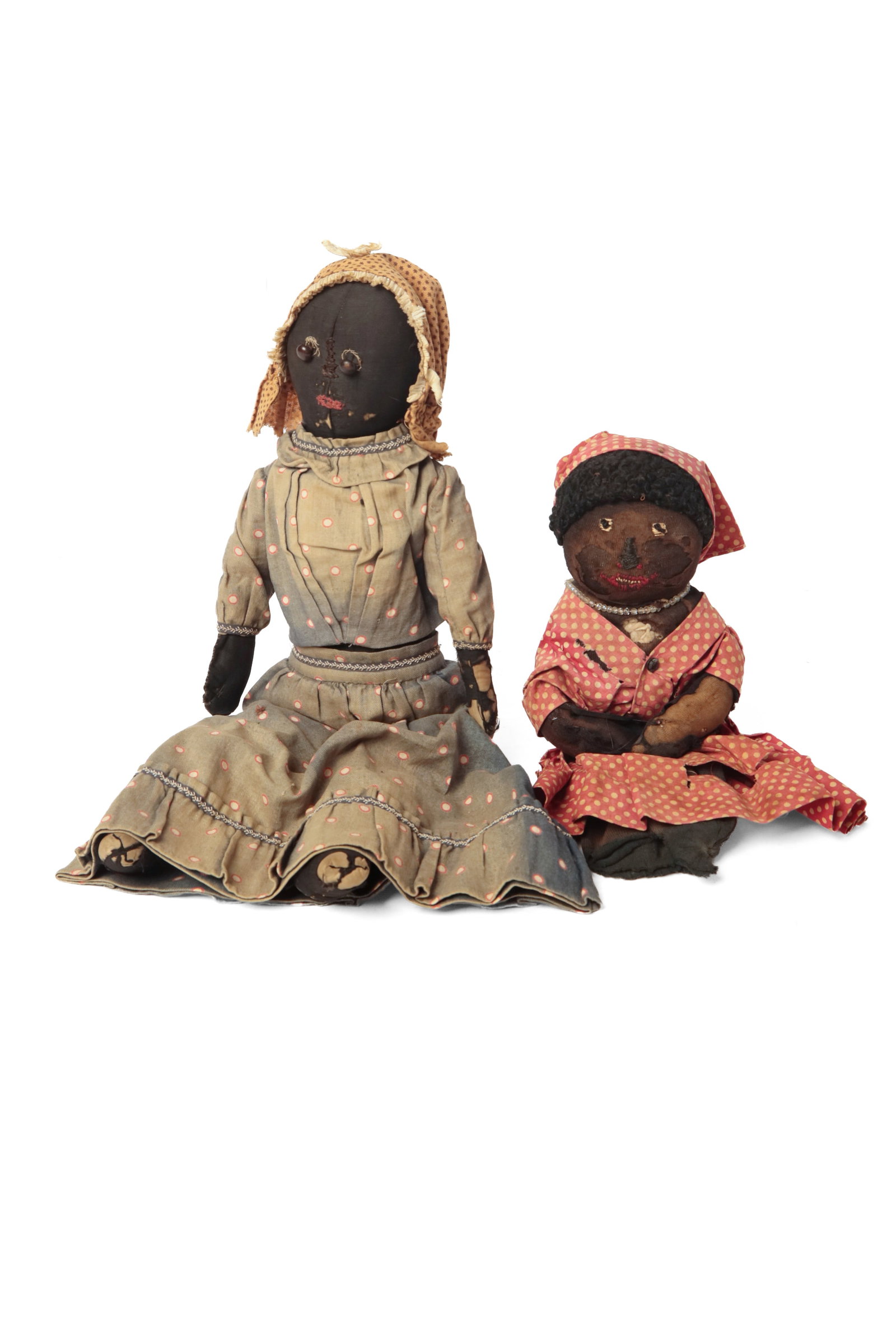 TWO FOLK ART BLACK AMERICANA CLOTH DOLLS.: TWO FOLK ART BLACK AMERICANA CLOTH DOLLS. American, late 19th or early 20th century. Both made of stuffed black cloth. One with button eyes and stitched nose and mouth, wearing a bonnet and polka dot