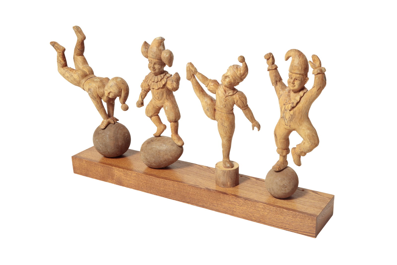 FOUR CARVED WOOD ACROBAT PAPIER-MACHE MOLDS.: FOUR CARVED WOOD ACROBAT PAPIER-MACHE MOLDS. European, late 19th Century. Male figures in different poses, dressed in clown-like clothes with hats. Two are on spheres, one on an egg, and one on a