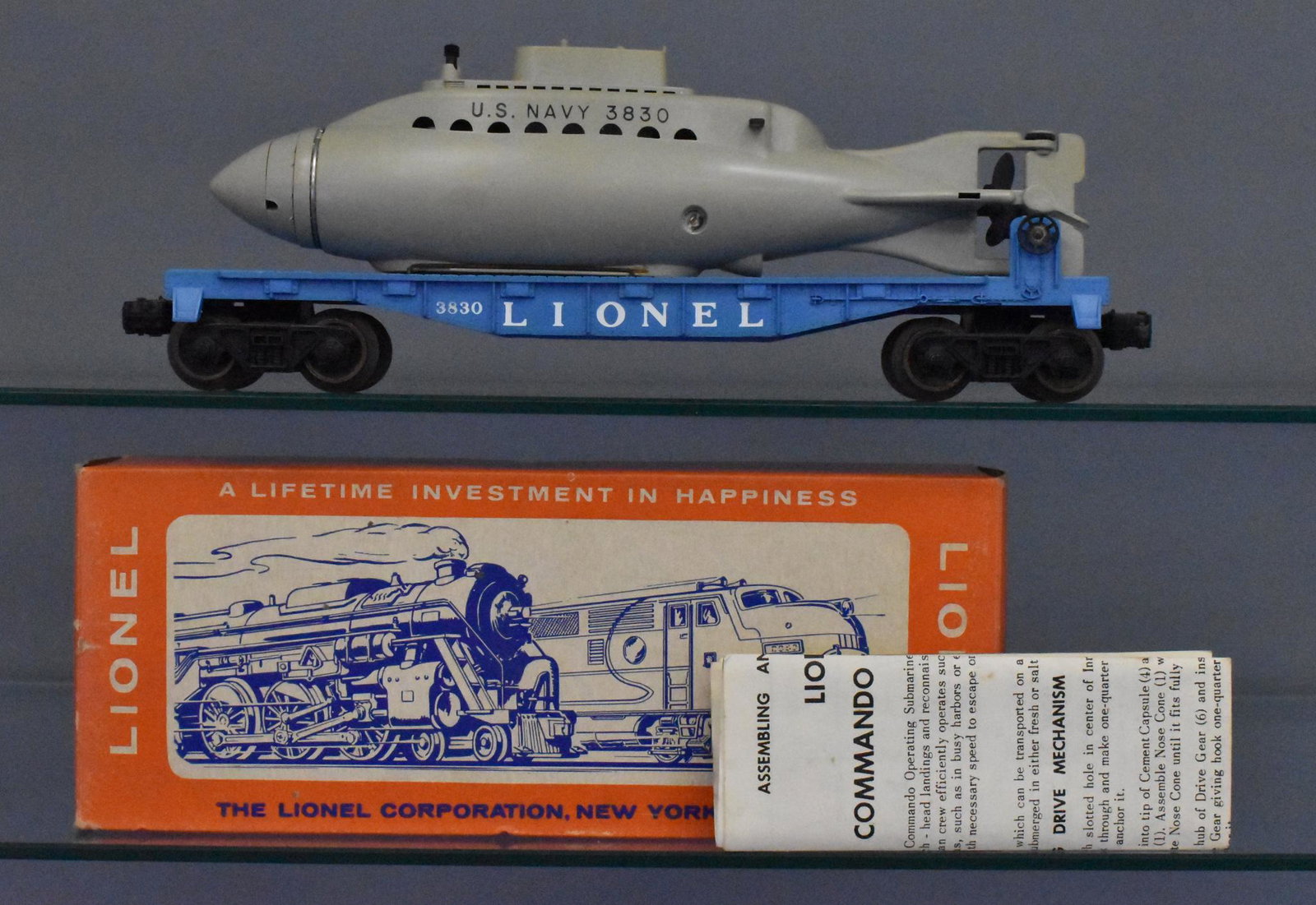 Lionel postwar O gauge 3830 flat car with operating: Car shows light run time with some oxidation to the wire hold downs for the submarine. The sub is complete with some discoloration and works, C6-7. the original box is complete with a nice original in