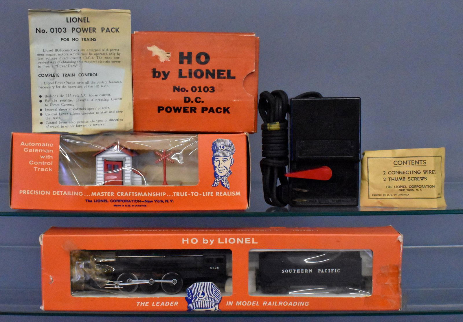 Group of Lionel postwar HO scale trains and accessories: Includes 0625LT Southern Pacific 4-6-2 steam locomotive and tender in a worn original box with tape repairs and original instruction sheet, 0145 automatic gateman w/ control track, used 0103 transform