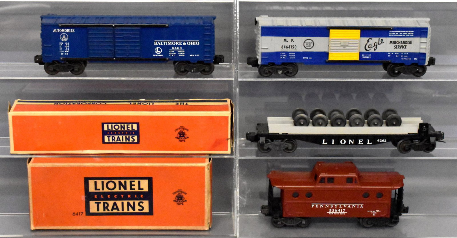 Four Lionel postwar O gauge freight cars with 2: Includes 6468 B&O box car, 6464-150 Missouri Pacific box car, 6262 wheel car and 6417 Pennsylvania porthole caboose, C7 with light run time, both original boxes have wear and missing flaps.