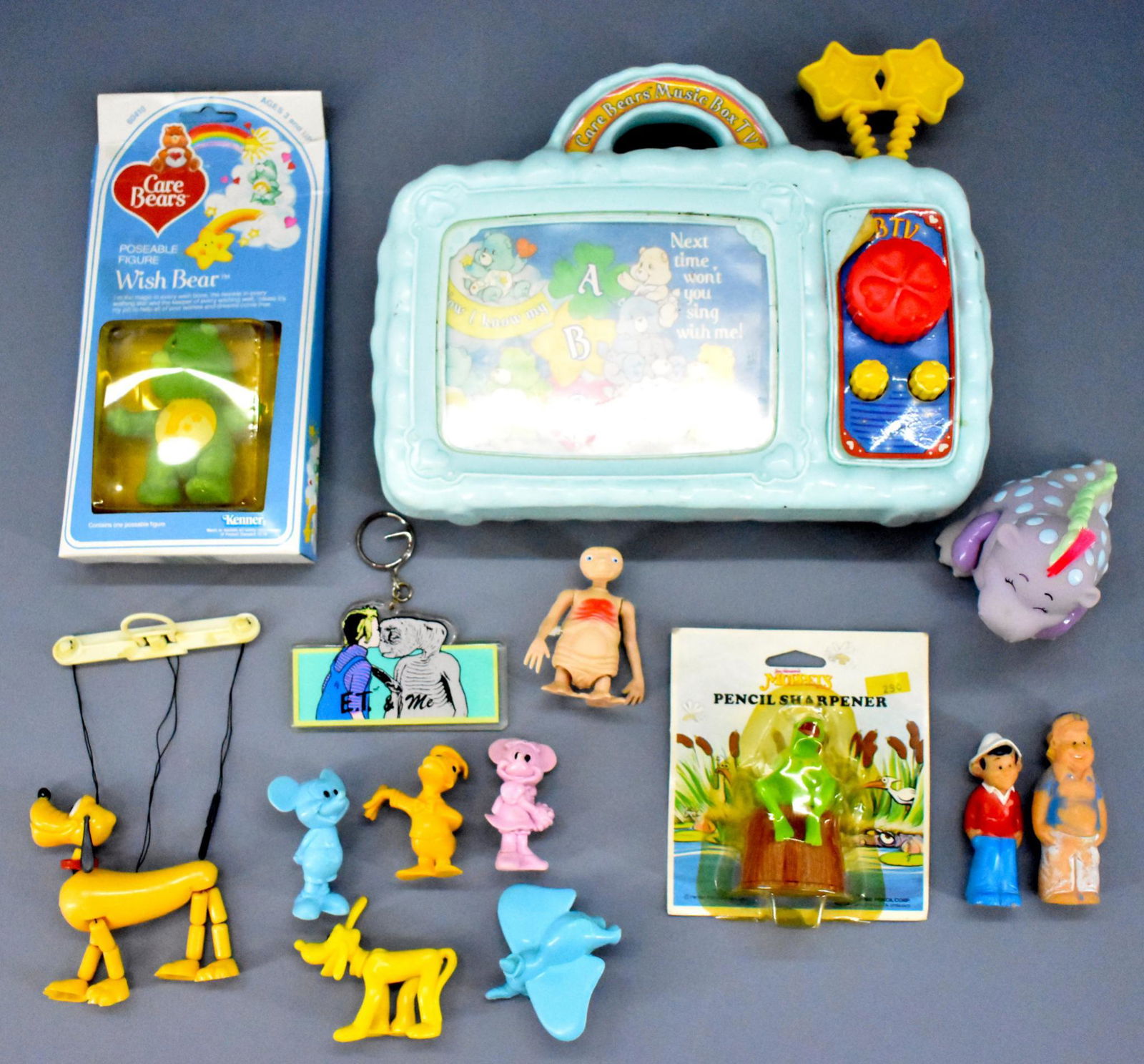 Group of assorted 80's small toys including Care Bears: Group includes a carded Kermit pencil sharpener, a Care Bear Wish Bear vinyl figure still sealed in original package, a windup ET toy, an ET keychain, 2 vinyl Gilligans Island figures, 5 Disney PVC fi