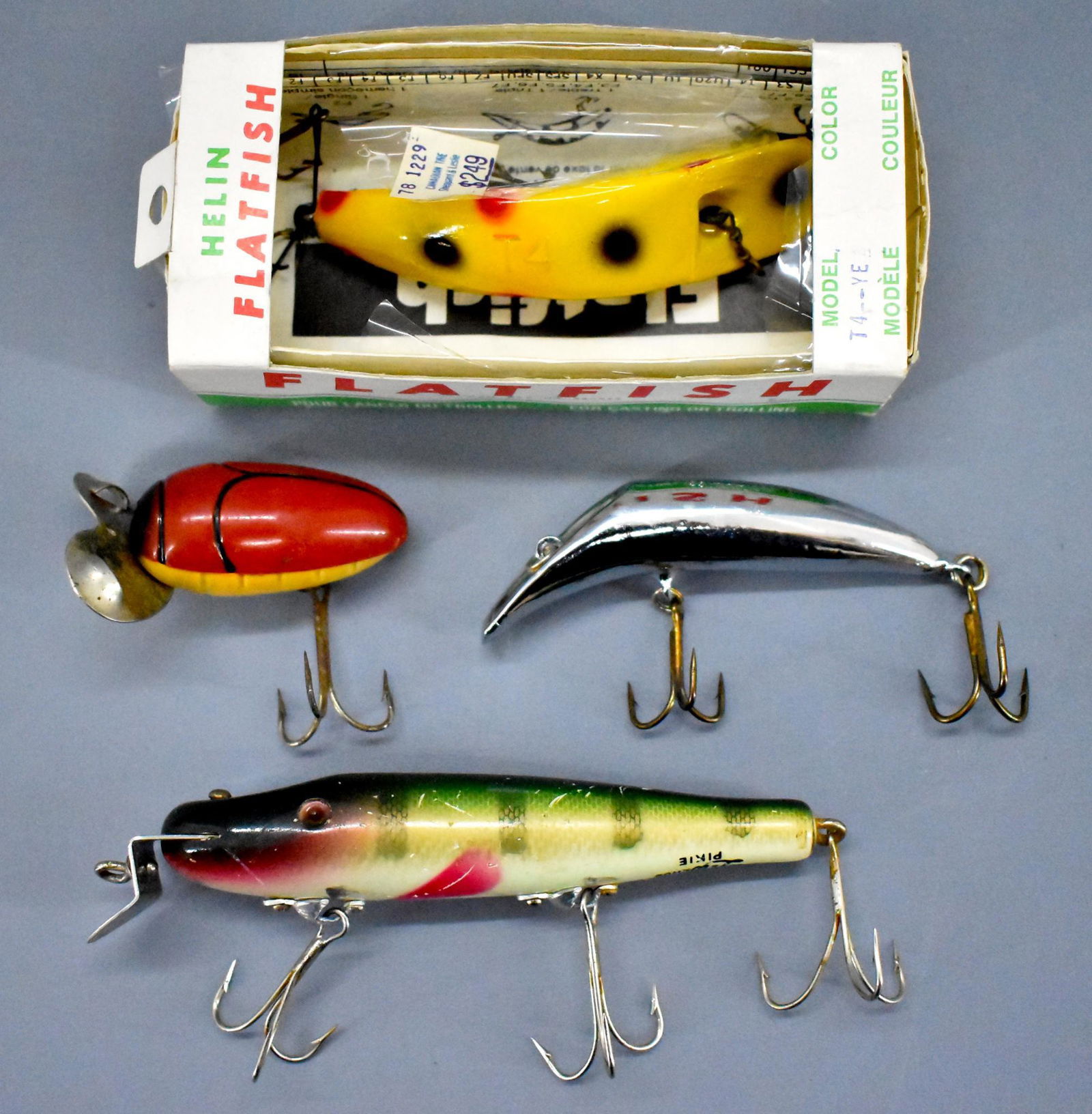 Four vintage fishing lures with one original box: Four vintage fishing lures with one original box. includes Millsite Paddle Plug, Creek Chub Pikie, Canadian Wiggler and Helin Flatfish, all in nice shape as seen in the photos.