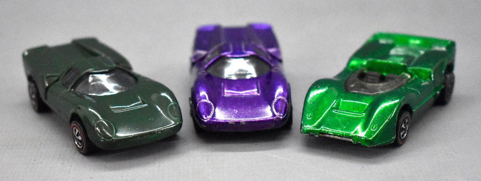 Three Redline Hot Wheels US casting race cars: Three Redline Hot Wheels US casting race cars to include a green McLaren M6A and two Lola GT70, on enamel green and one purple. All three are clean with minor paint / play wear and have nice bases.