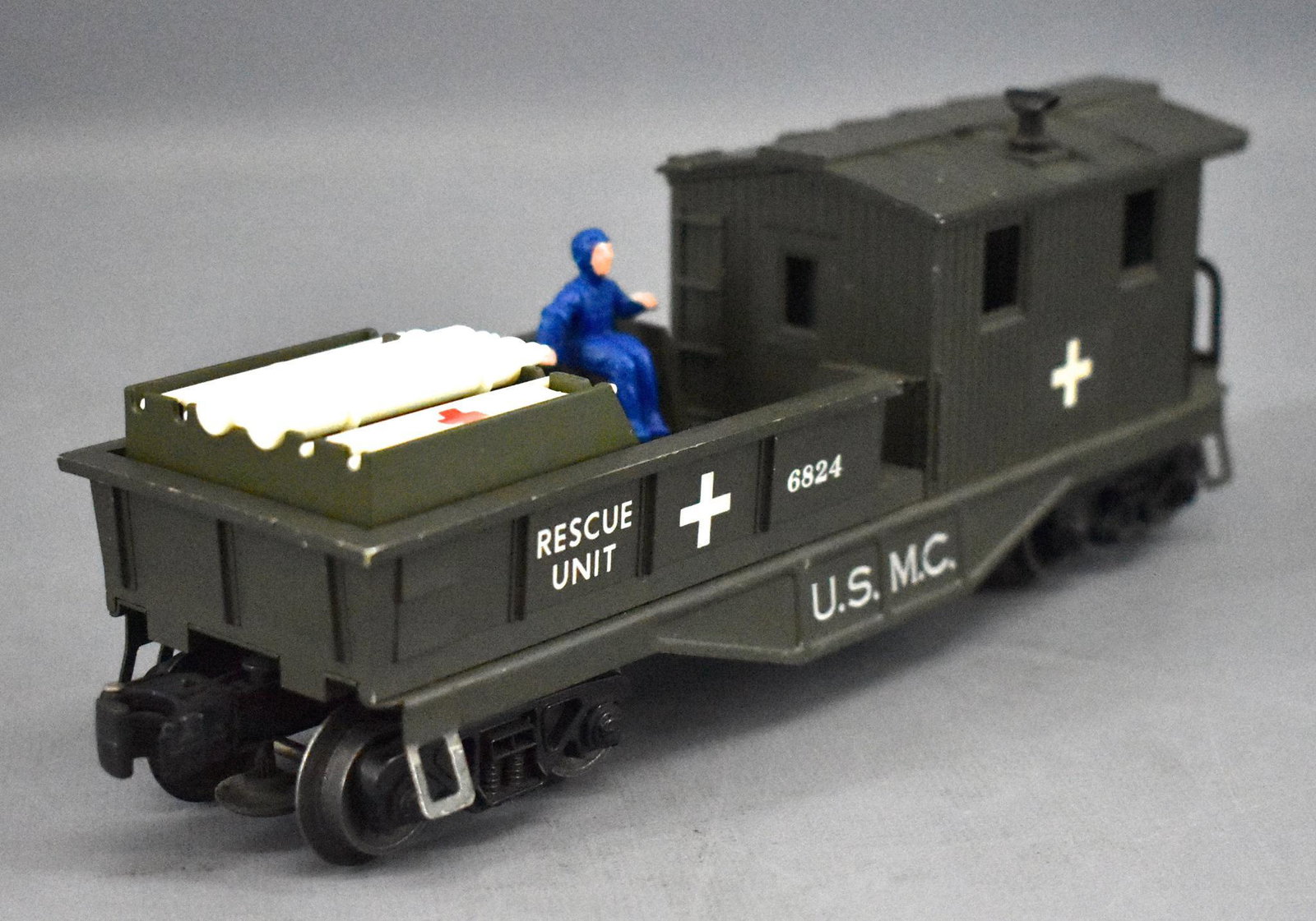 Lionel postwar O gauge 6824 USMC olive drab rescue: Lionel postwar O gauge 6824 USMC olive drab rescue caboose with reproduction figure, stretcher and oxygen tanks, otherwise C7 with some minor paint loss from the raised details on the roof.