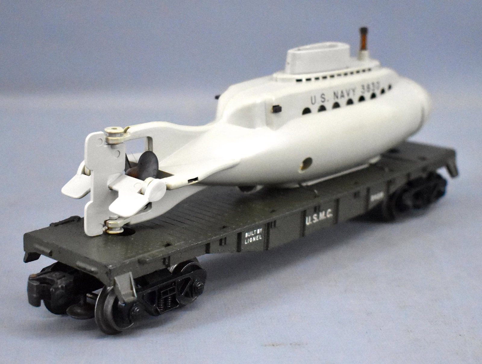 Lionel postwar O 3820 USMC olive drab flat car with: Lionel postwar O 3820 USMC olive drab flat car with submarine. Car is missing the entire brake stand and the submarine is missing the rubber band inside and has apparently been glued together in front