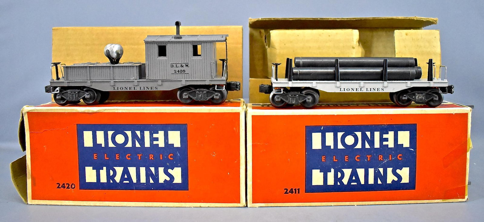 Lionel postwar O 2411 flat car and 2420 caboose in: Lionel postwar O 2411 flat car with one original and two reproduction pipes plus a 2420 D.L. & W. caboose with a chipped roof in original boxes, C5-6 with fair original boxes and one correct liner and