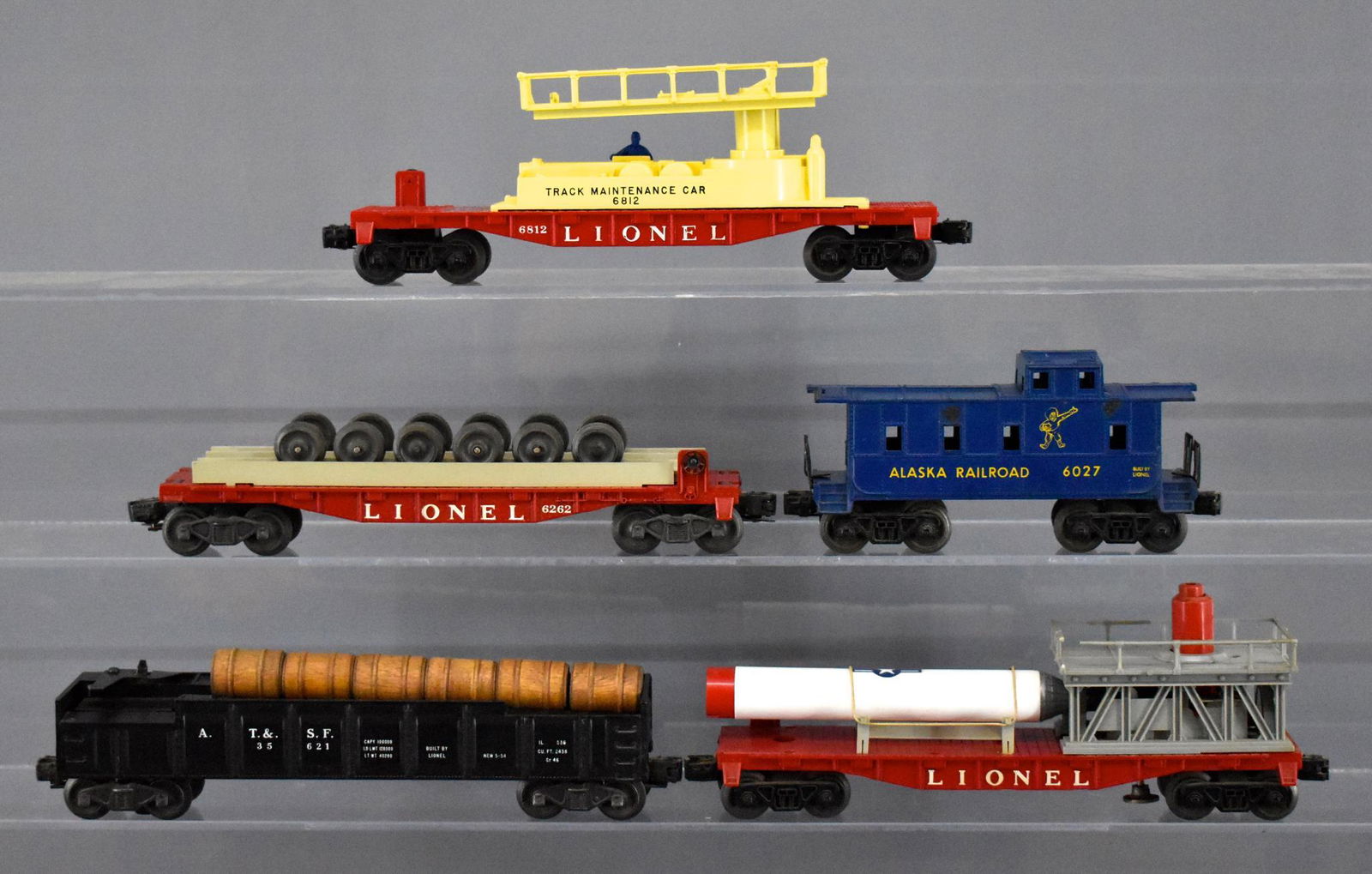 Group of five damaged Lionel postwar O gauge train cars: Group of 5 Lionel postwar O gauge train cars. Group includes 6027 Alaska Railroad Caboose with 2 burn marks on one side, missing one ladder , 6812 Track Maintenance car that has one railing top bar mi